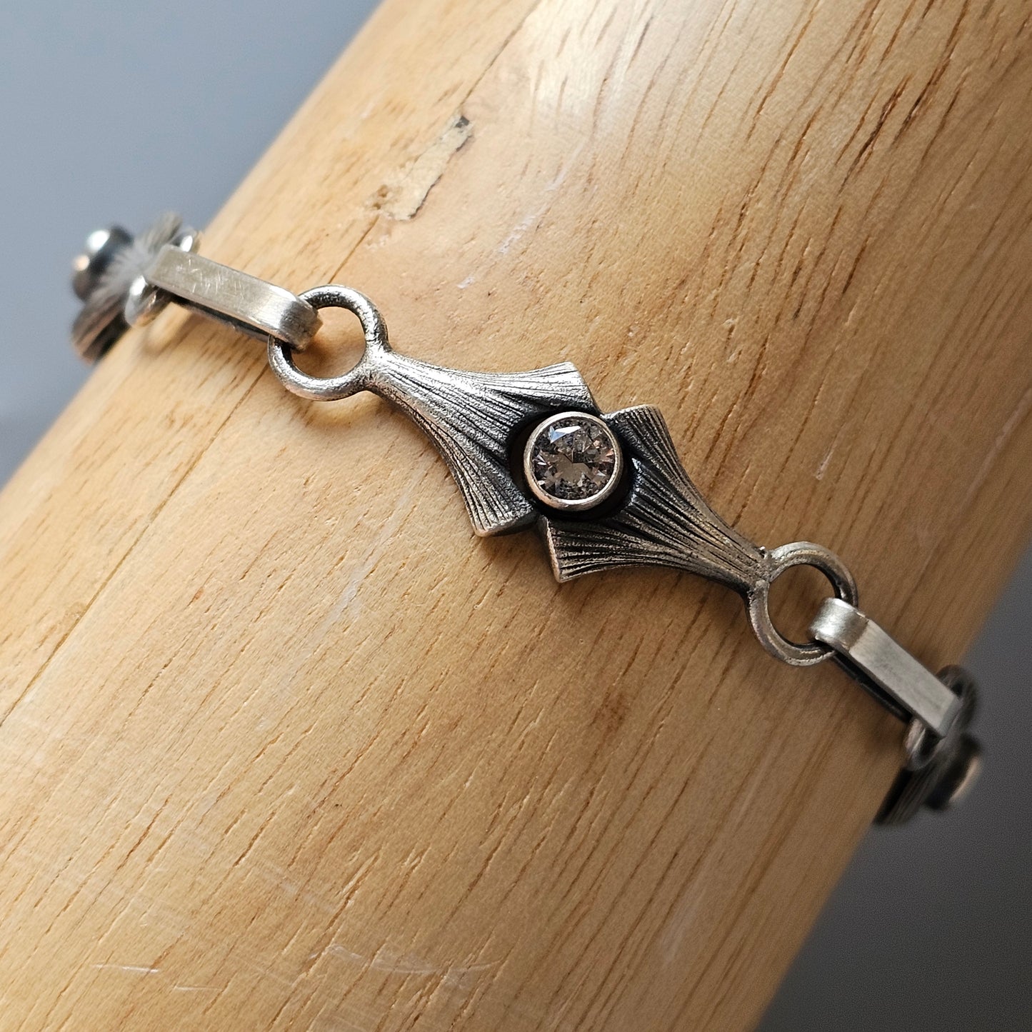 Silver bracelet with a central diamond-set geometric design.