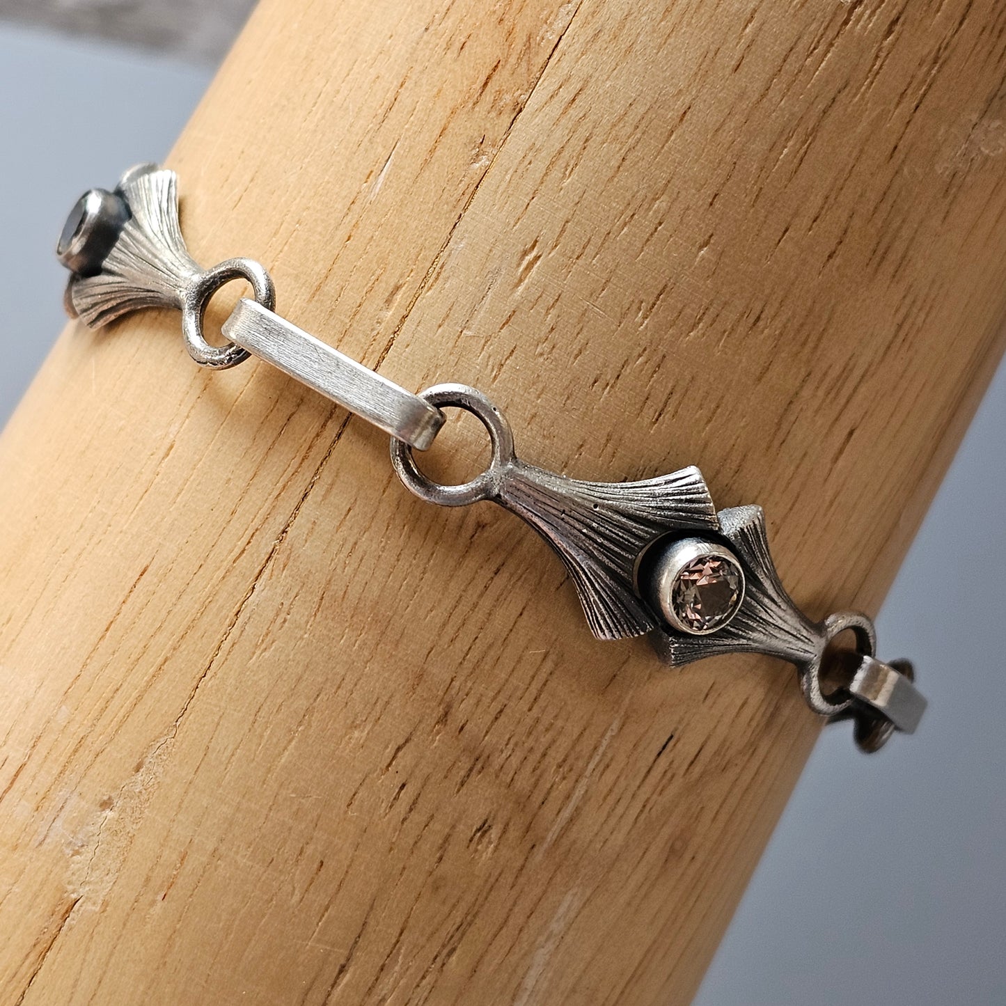 Silver bracelet with an art nouveau-inspired design featuring a central gemstone.