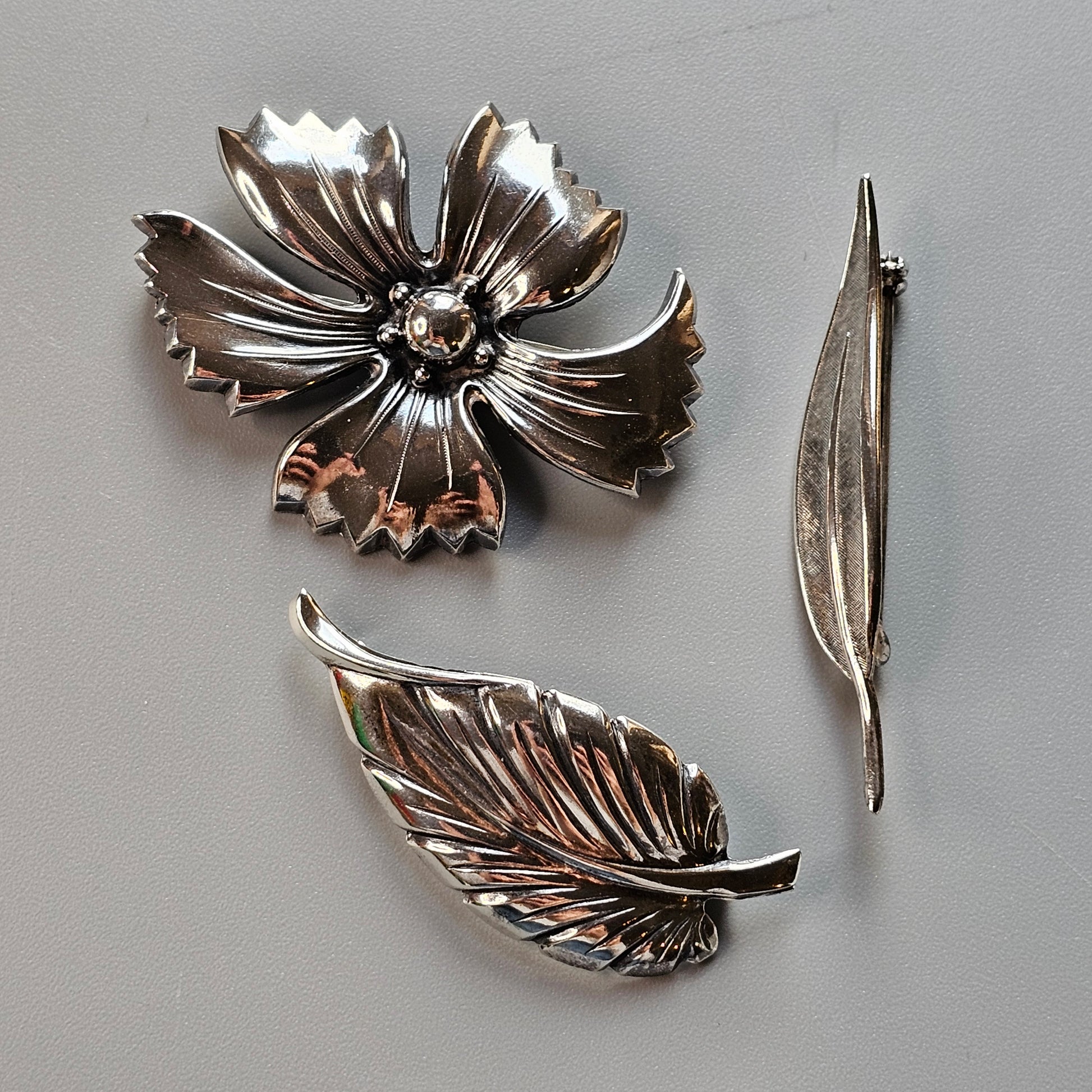 Silver floral brooch with detailed petals and leaves.