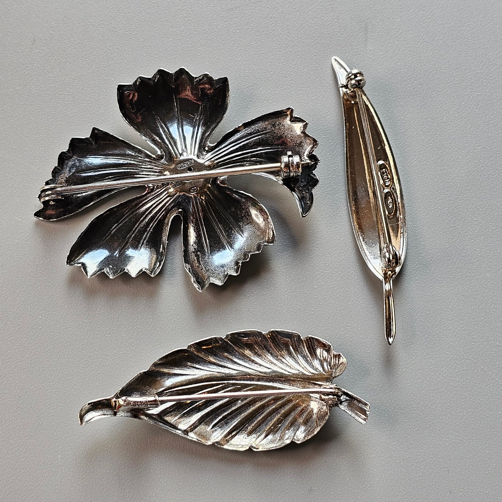 Silver floral brooch with petals and two accompanying leaf-shaped pins.