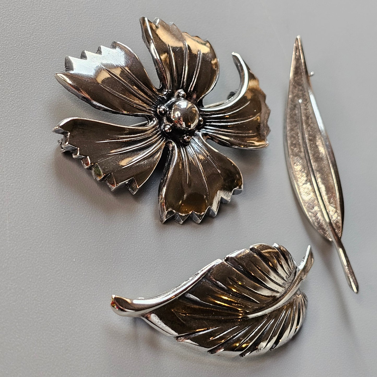 Metallic flower-shaped brooch or pin with separate leaf components.