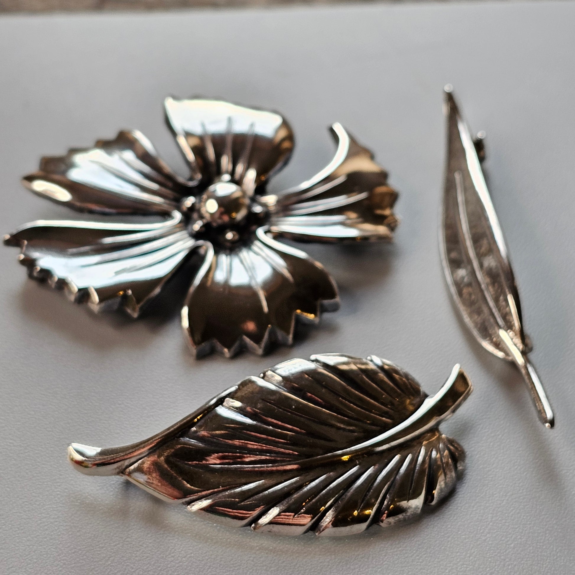 Metallic floral brooch with separate leaf-shaped pieces.