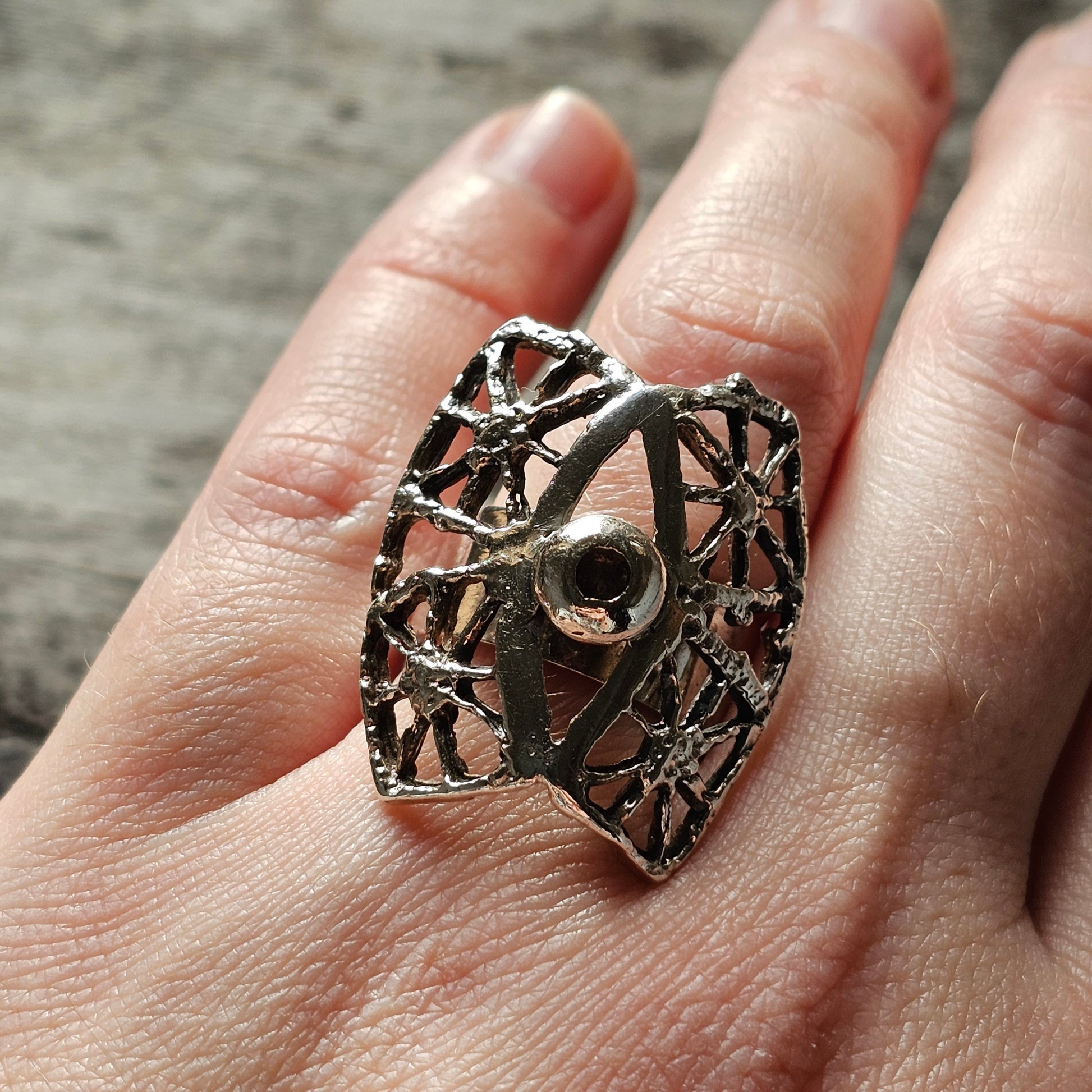 Ornate silver ring with an intricate geometric web-like design.