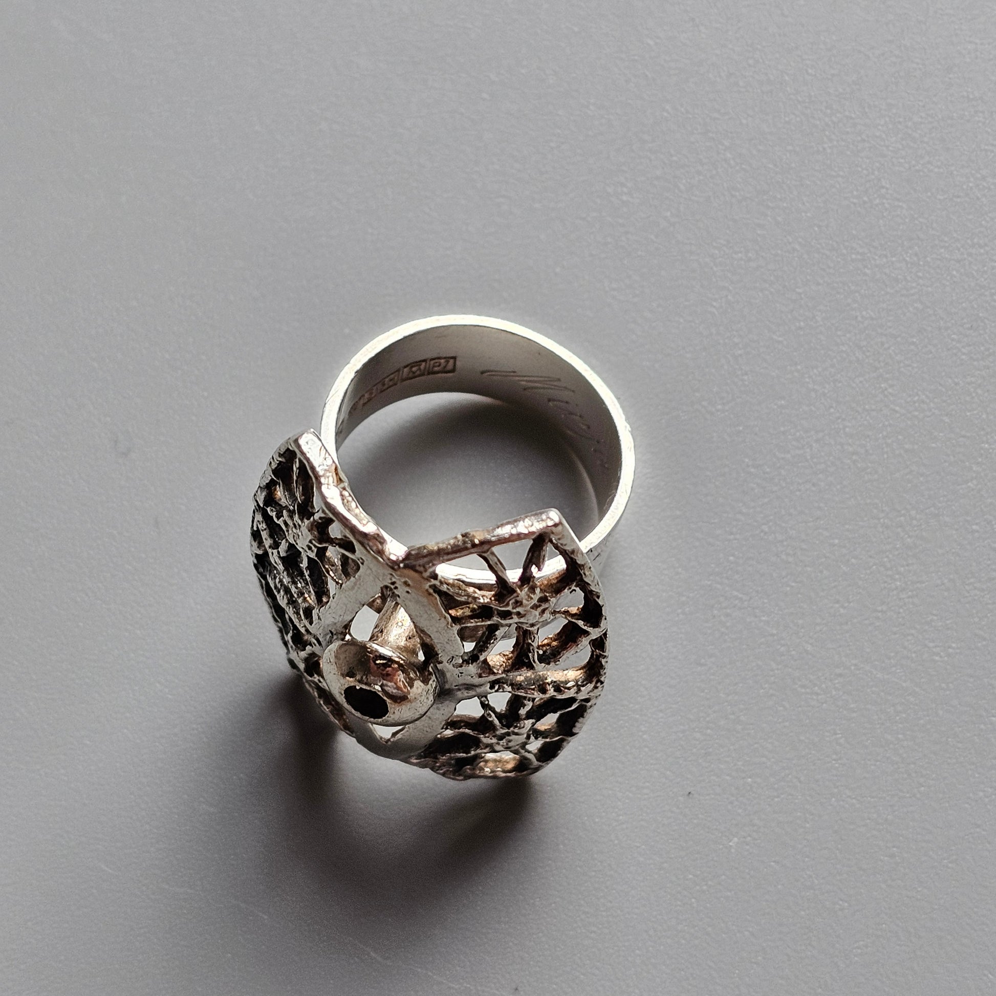 Ornate silver ring with intricate floral or leaf-like cutout design.