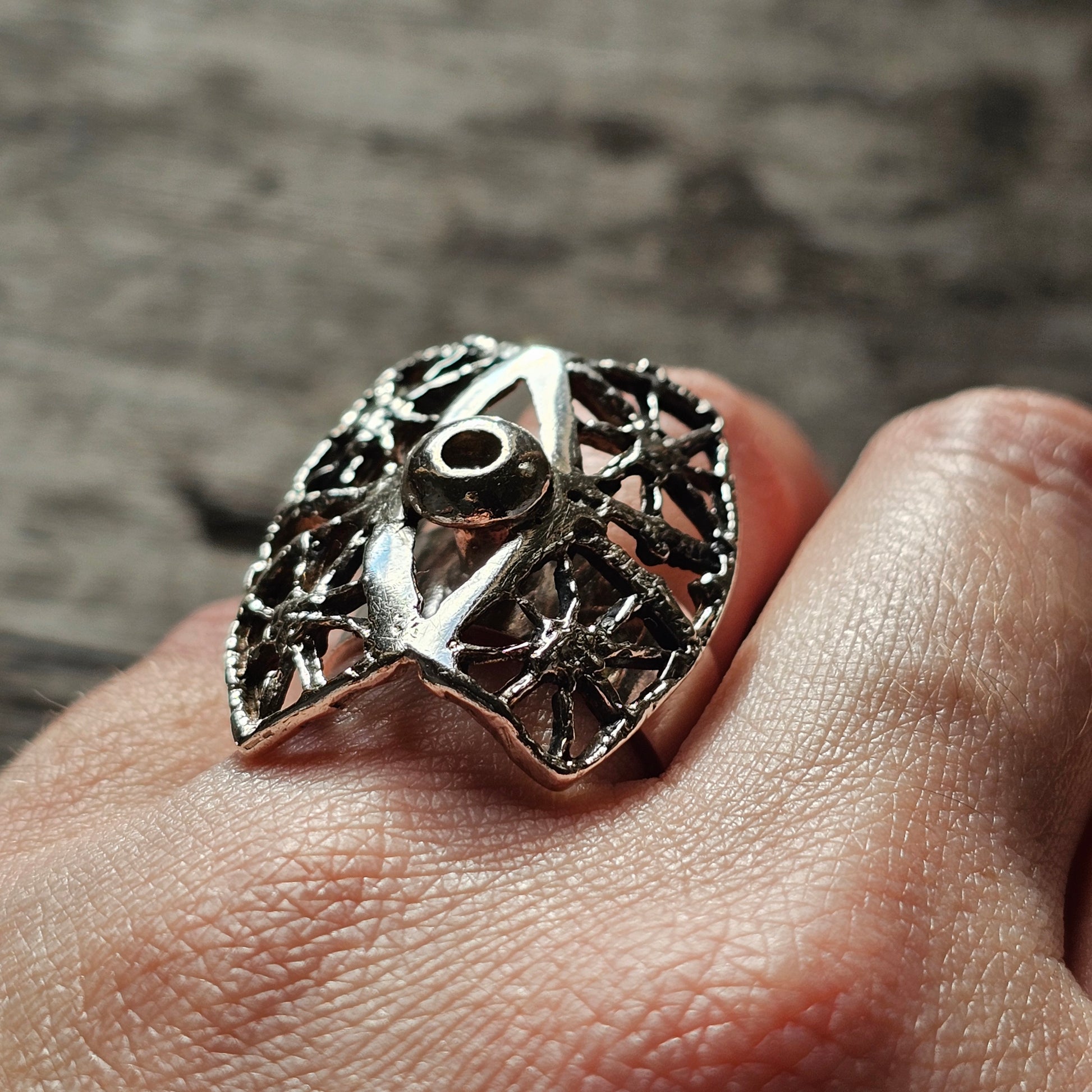 Ornate silver ring shaped like an owl’s face with intricate filigree details.