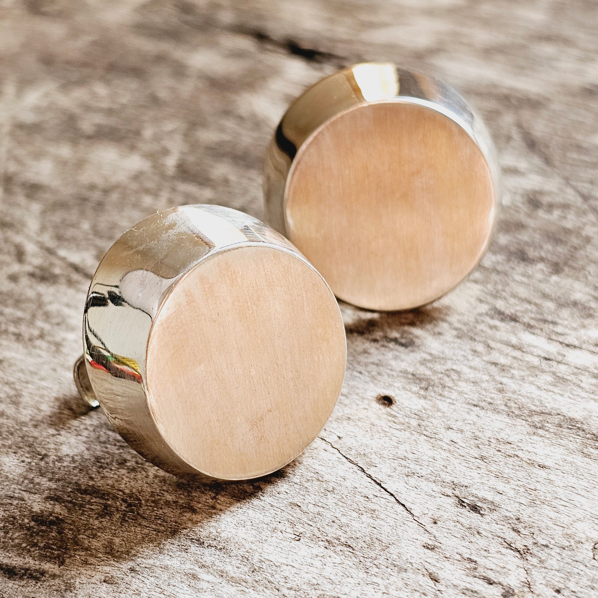 Pair of round, metallic stud earrings with flat faces.