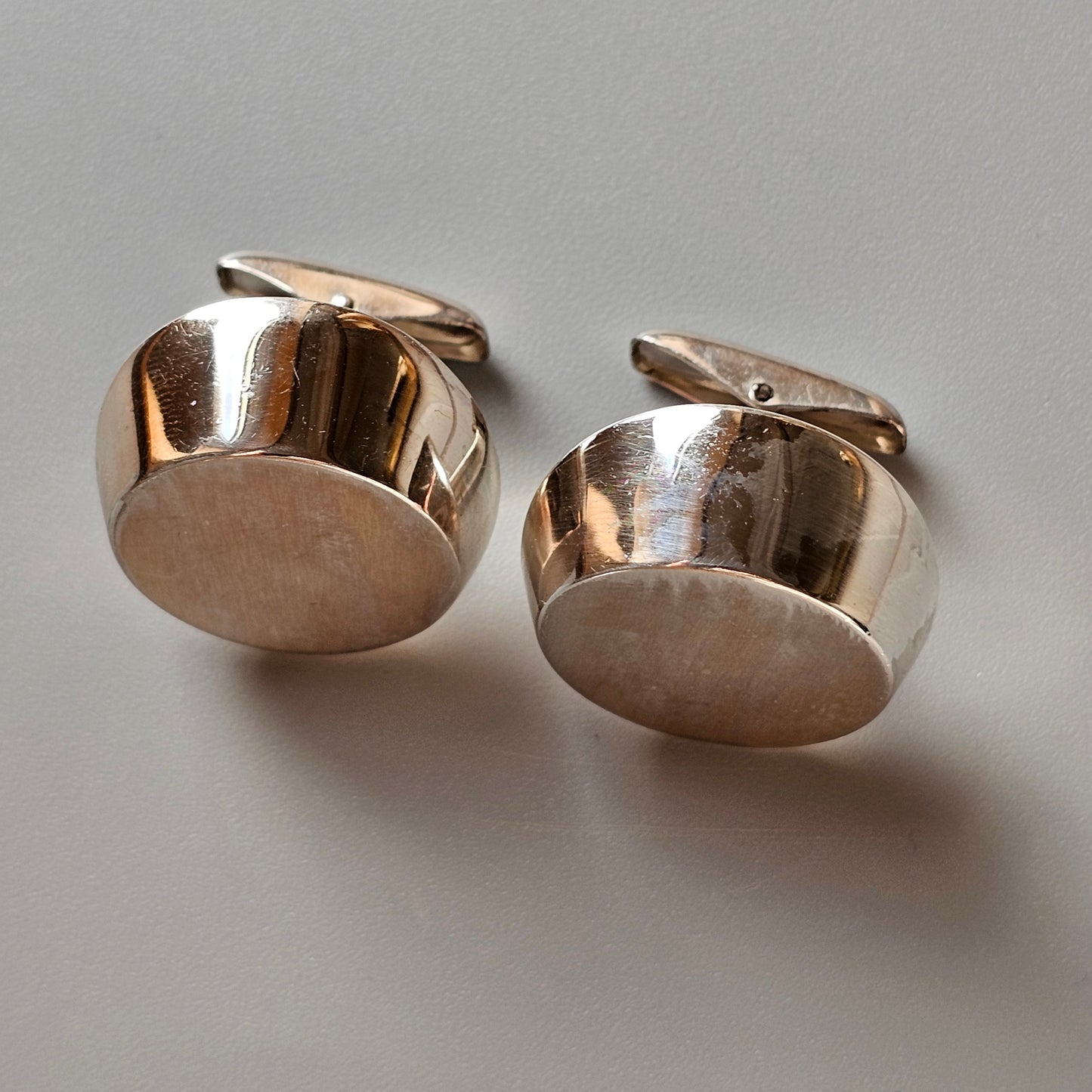 Pair of round, silver-colored metal cufflinks with a polished finish.