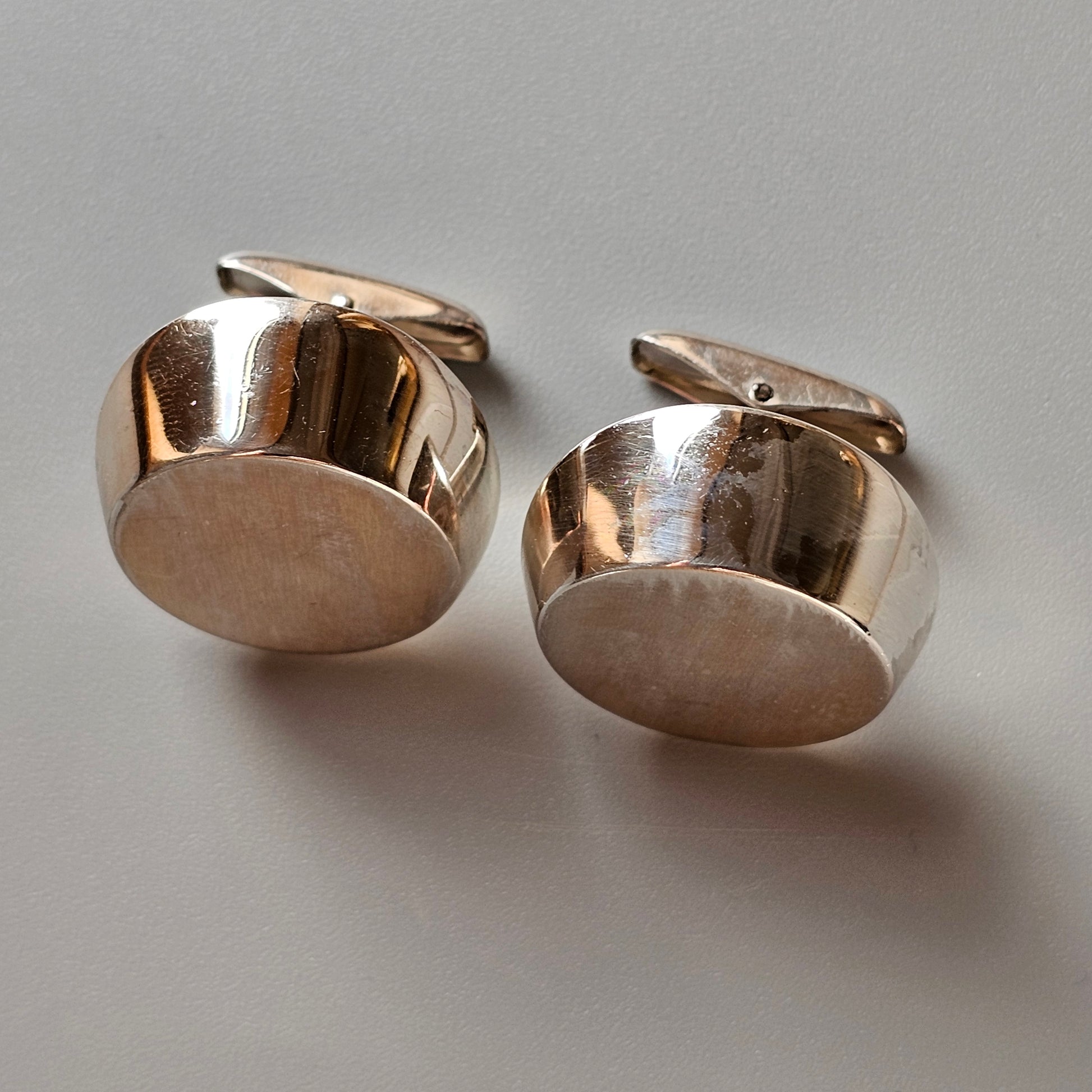 Pair of round, silver-colored metal cufflinks with a polished finish.