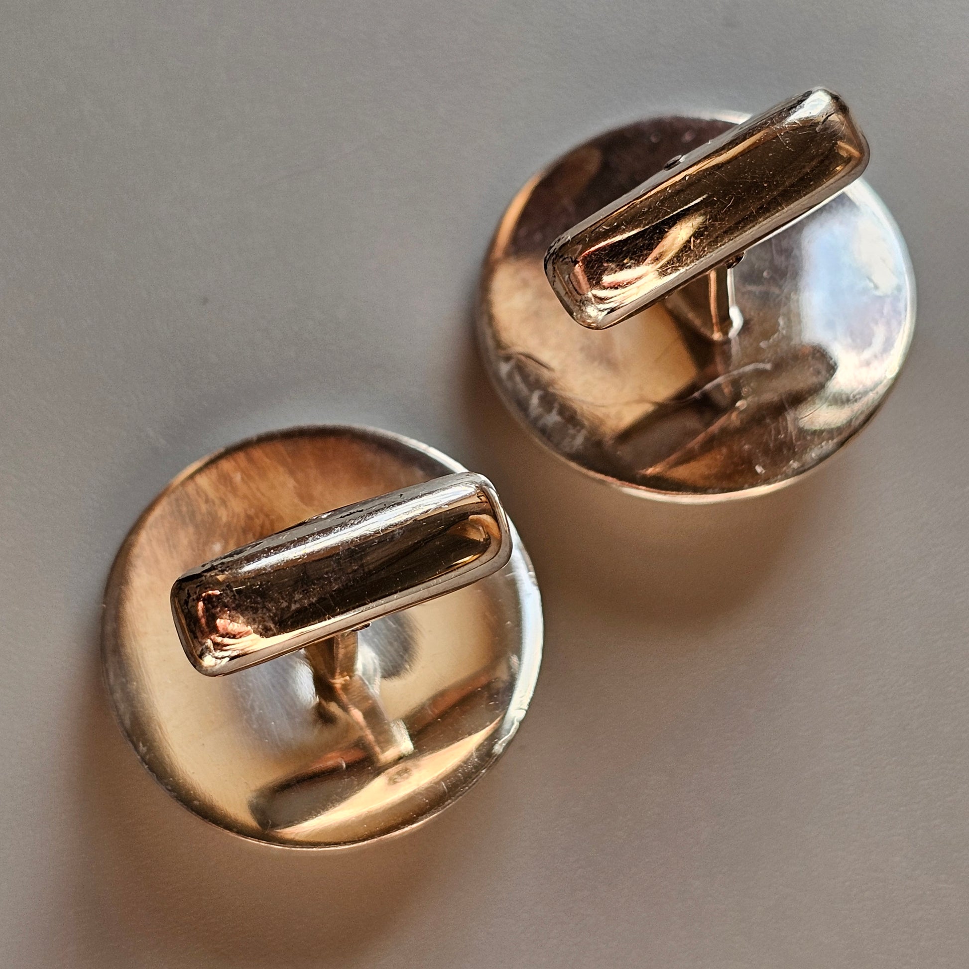 Pair of round gold cufflinks with cylindrical bars.