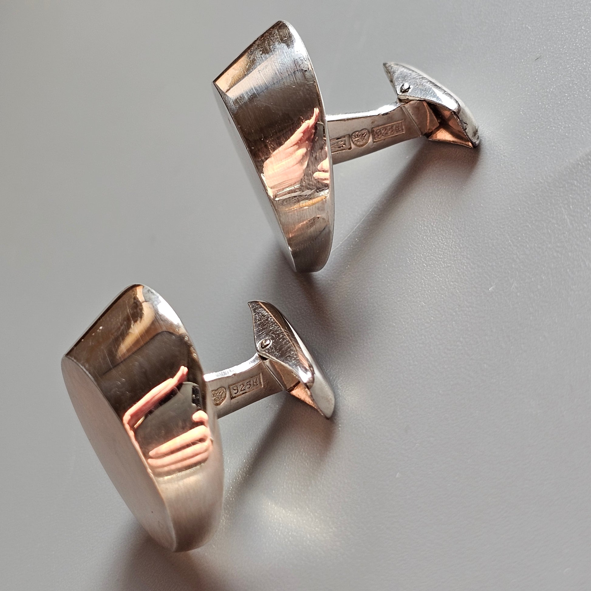 Pair of shiny metallic cufflinks with a smooth, curved design.