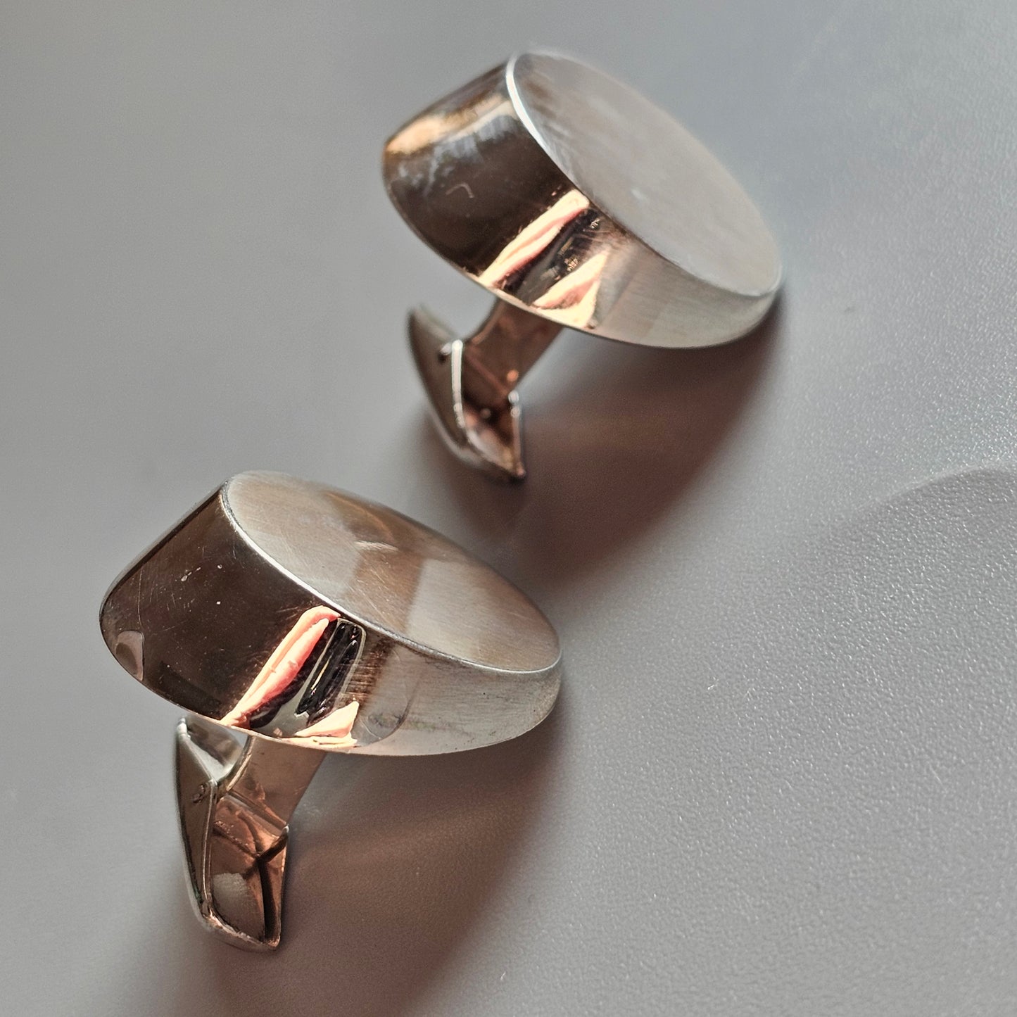 Pair of silver cufflinks with rounded tops and rectangular bases.