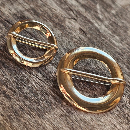 Gold circular brooches or pins with horizontal bars across their centers.