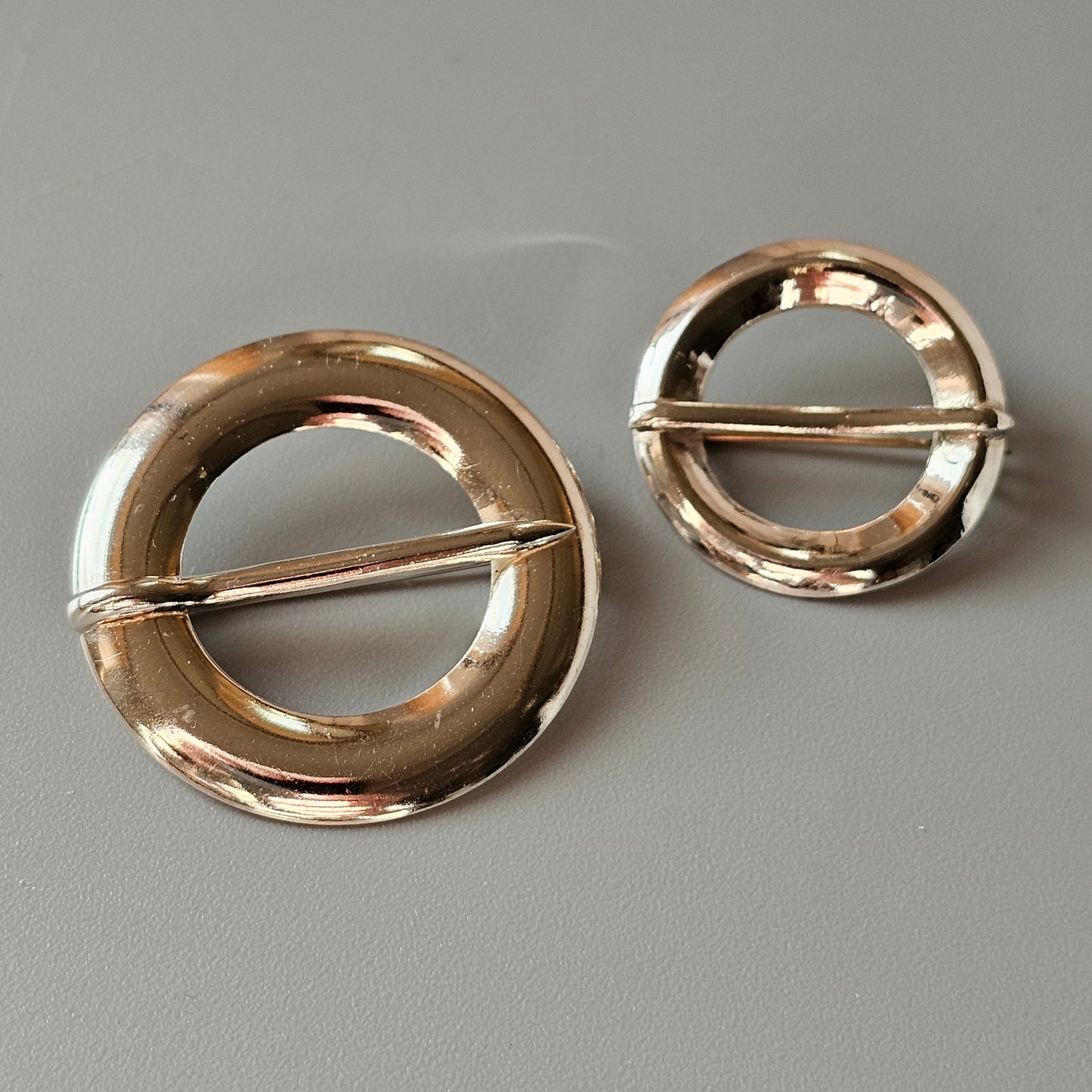 Two circular gold-toned metal buckles with central bars.