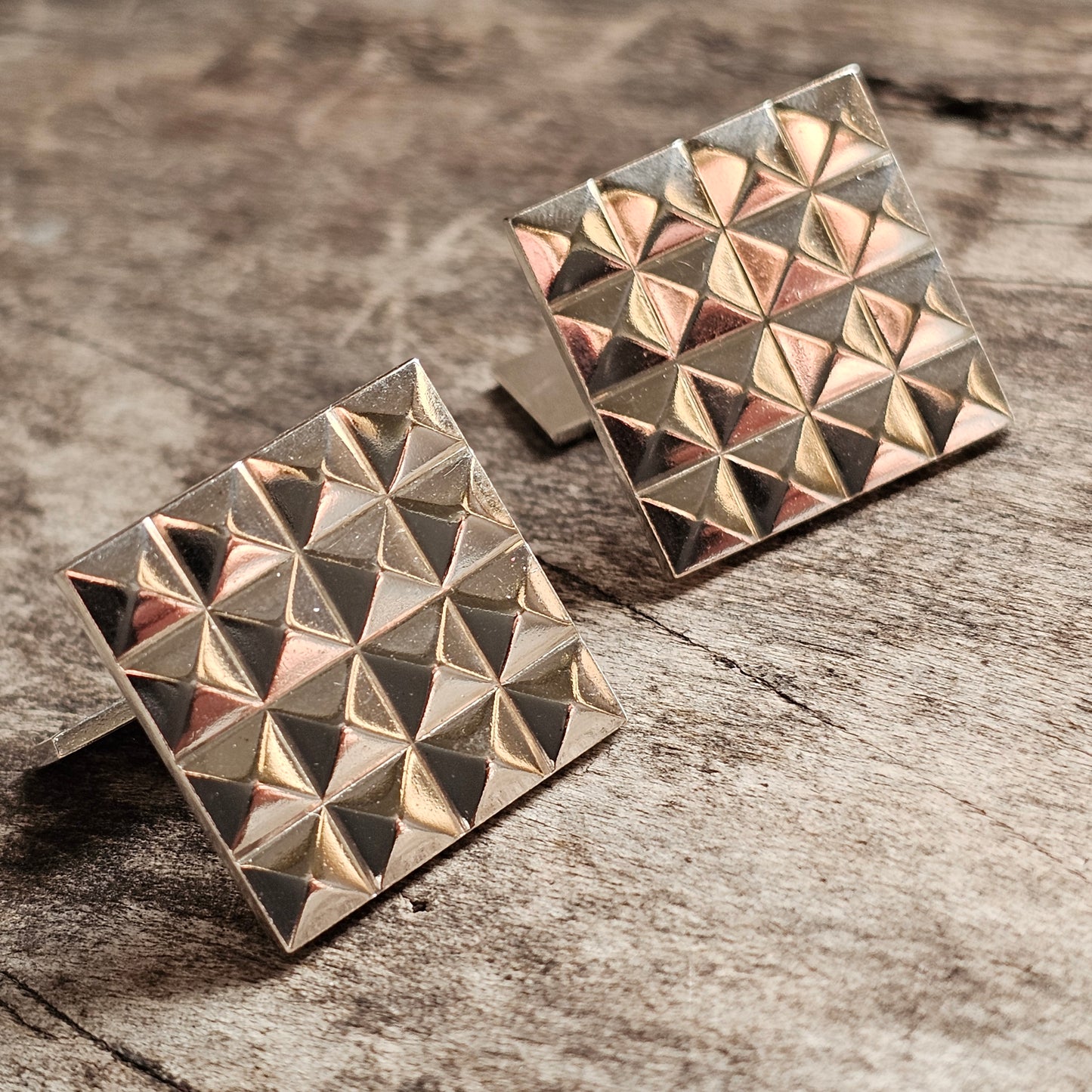 Pair of square gold-toned cufflinks with a geometric pyramid pattern.