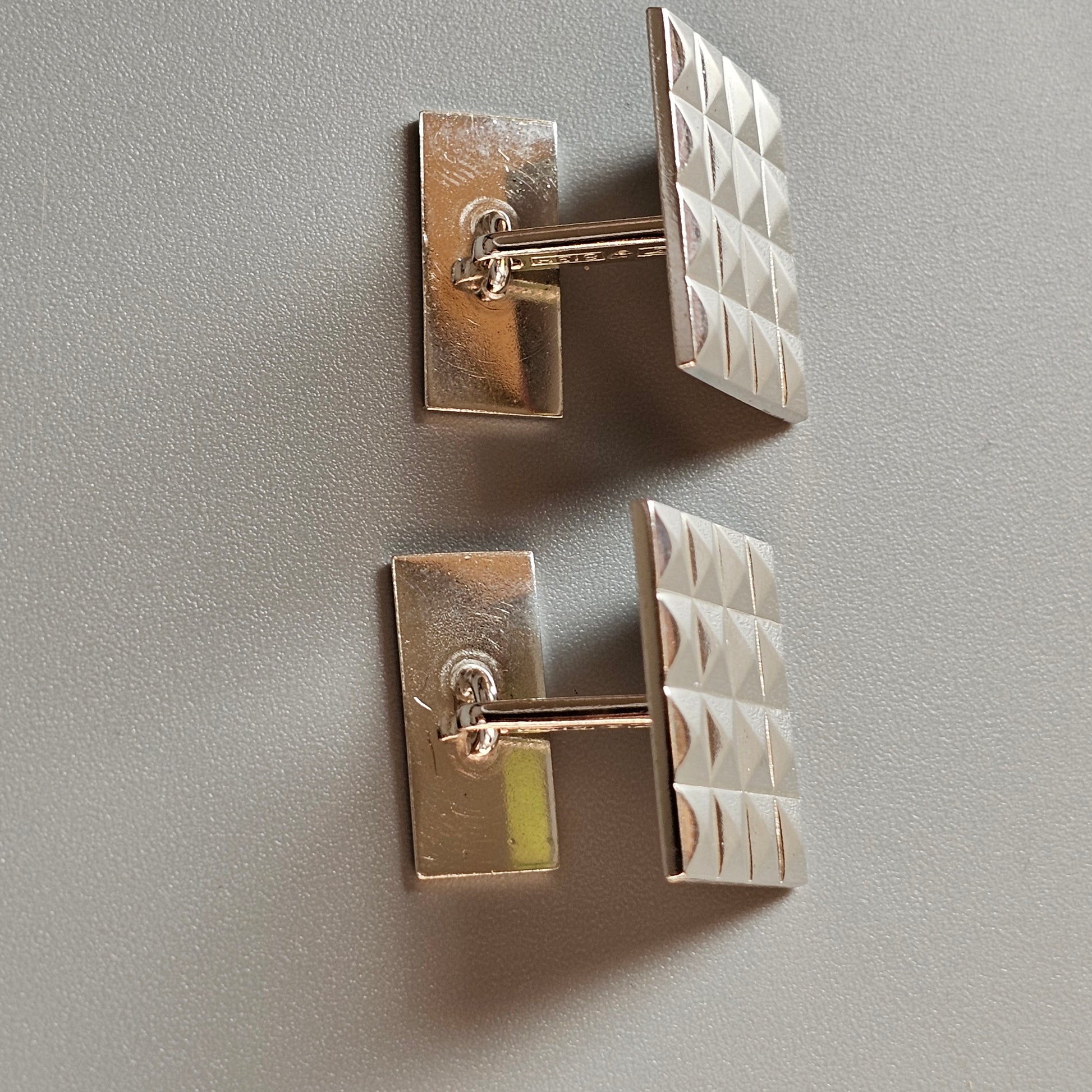 Pair of silver cufflinks with textured square faces.