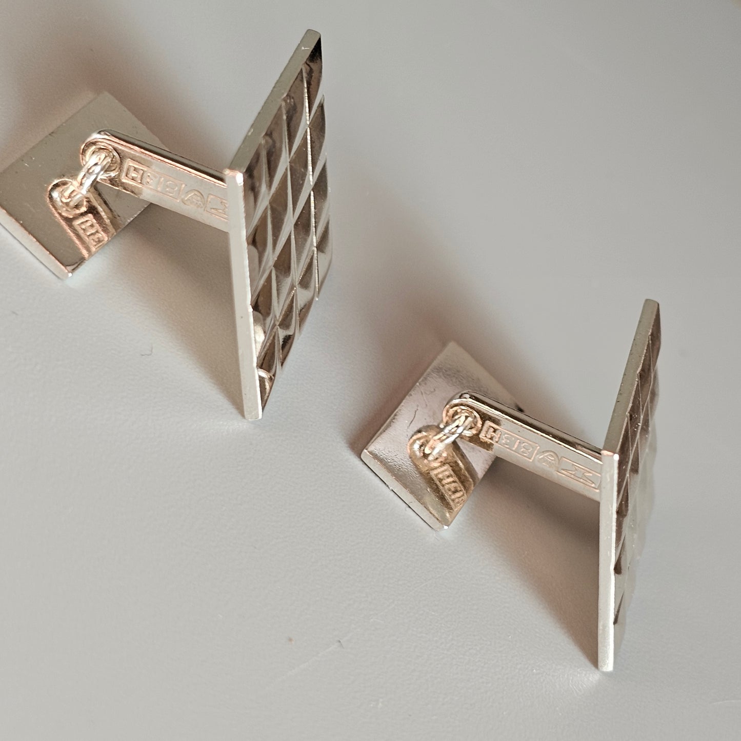 Pair of silver-toned cufflinks with square lattice designs.