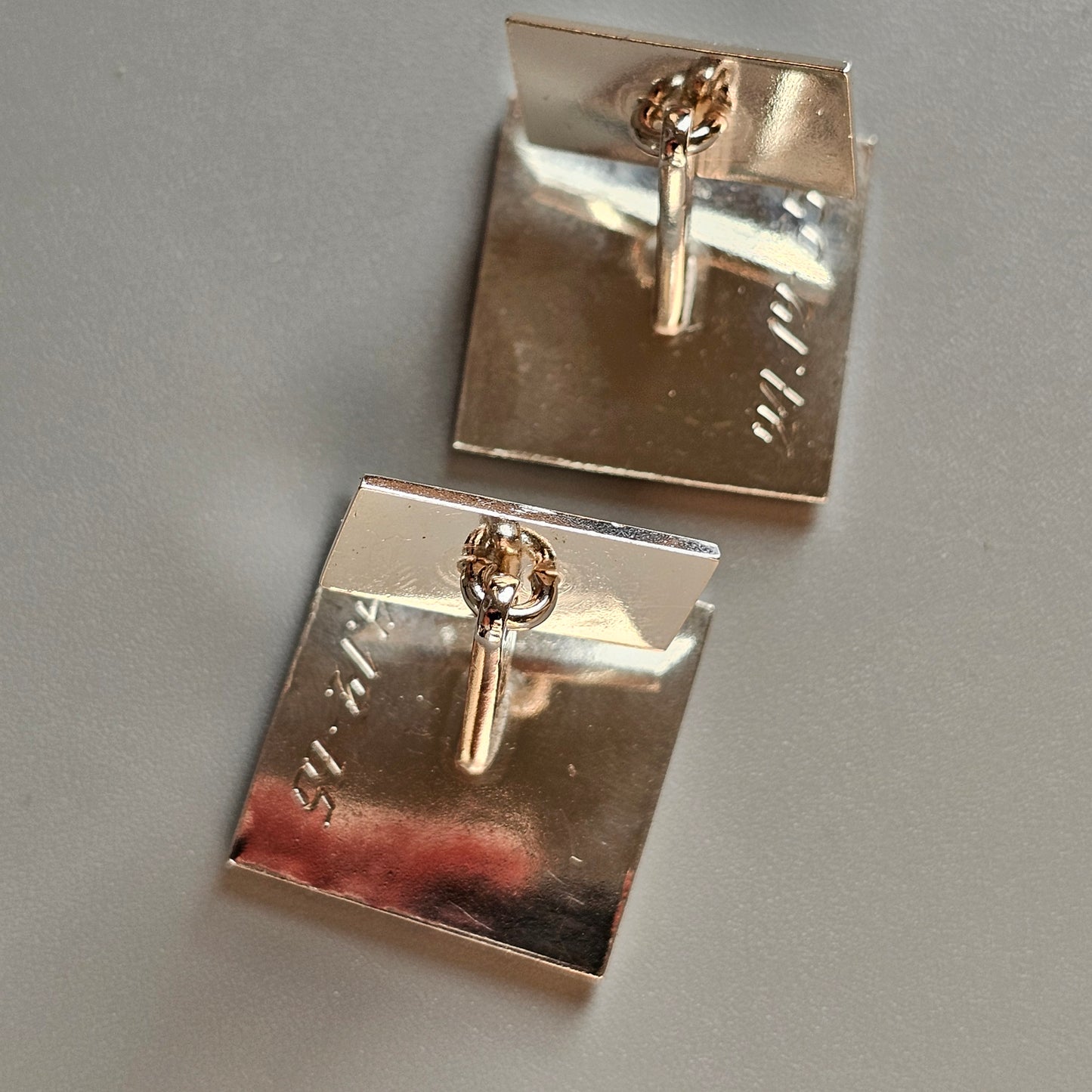 Pair of square silver cufflinks with gold-colored key designs.