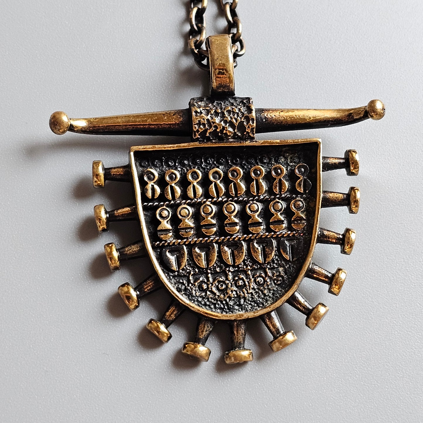 Ornate bronze pendant necklace with intricate designs and dangling elements.