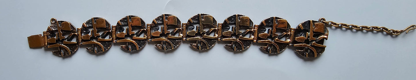 Ornate copper-toned bracelet with skull-shaped links connected in a row.