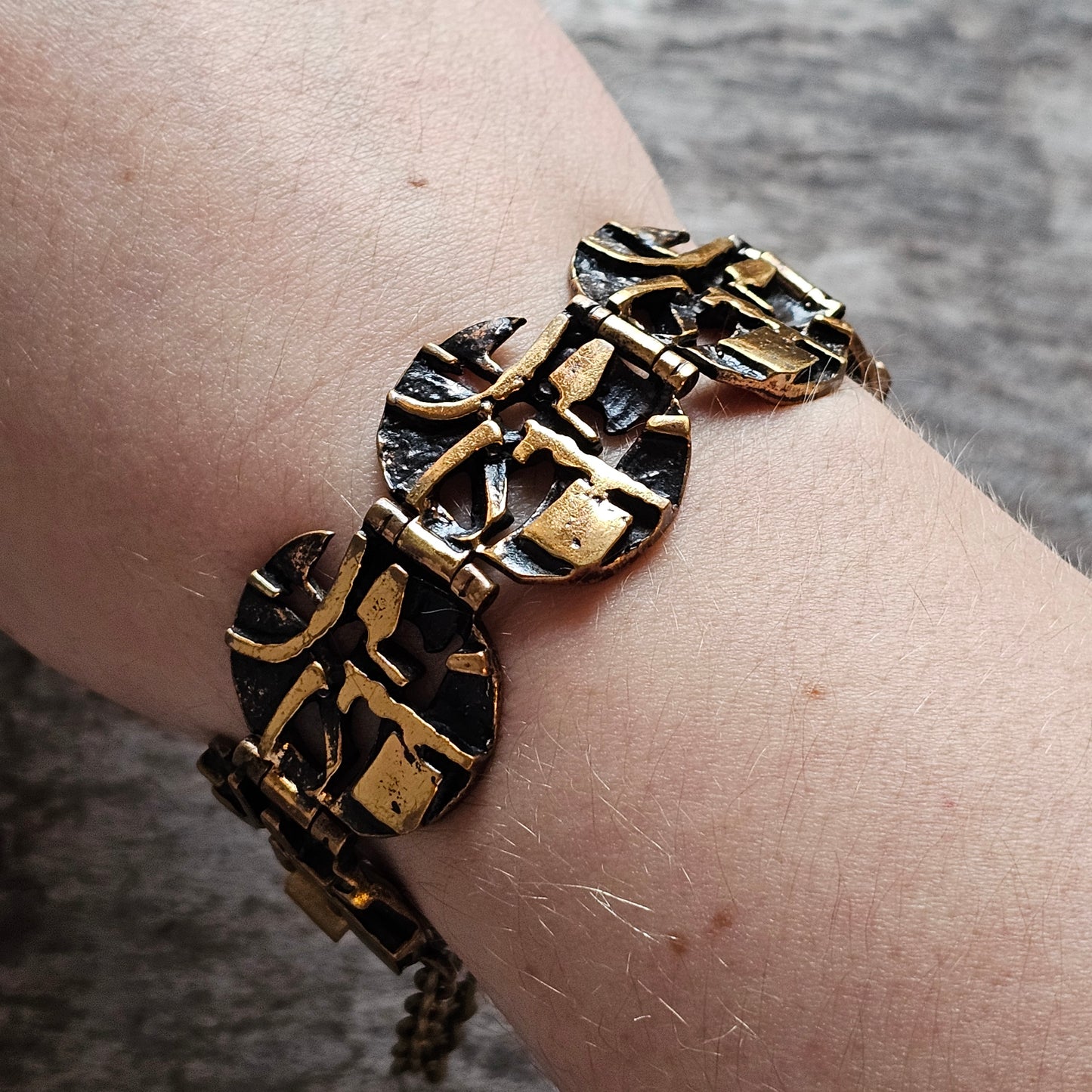 Bracelet with circular black and gold patterned beads worn on a wrist.