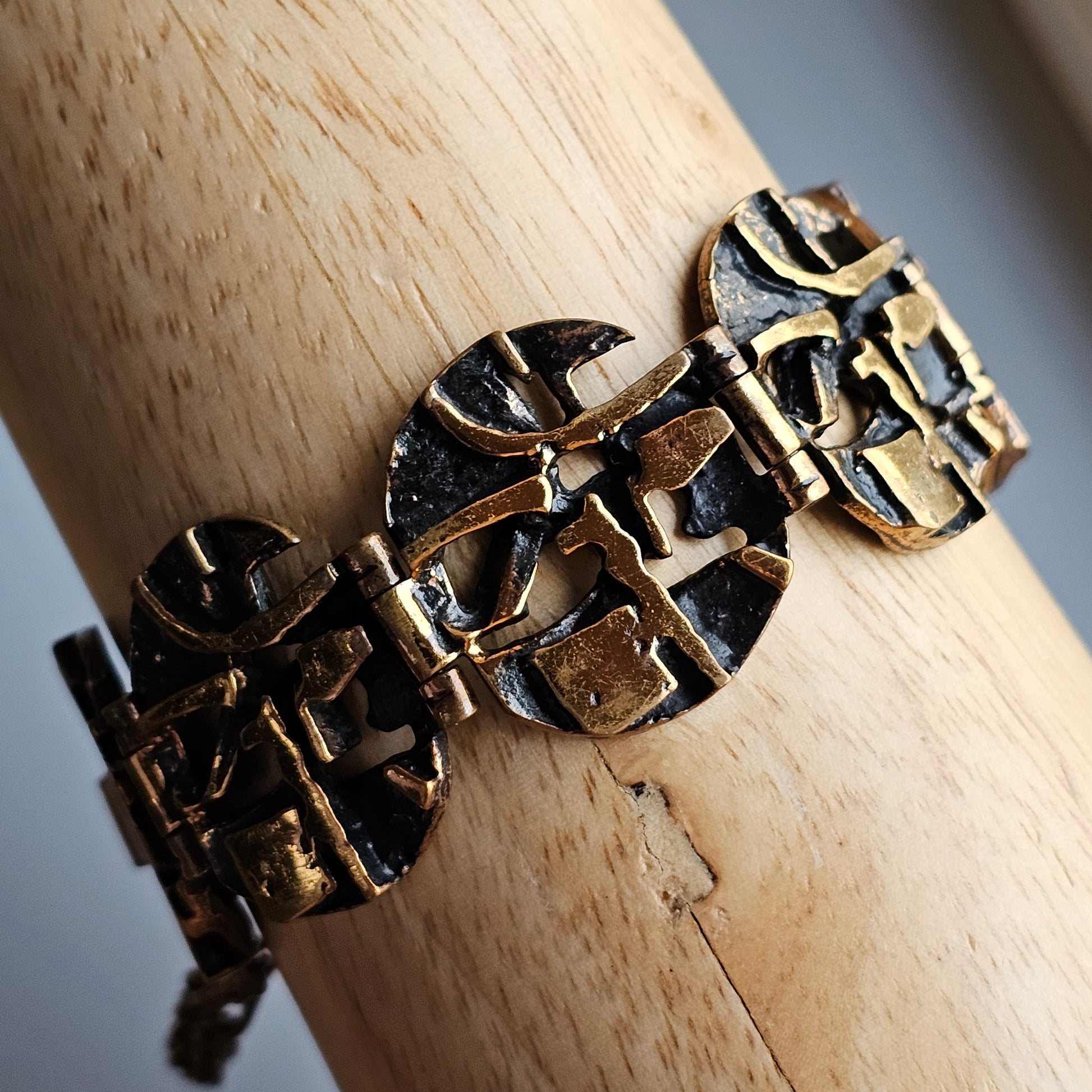 Ornate gold-toned bracelet with abstract geometric designs on circular links.