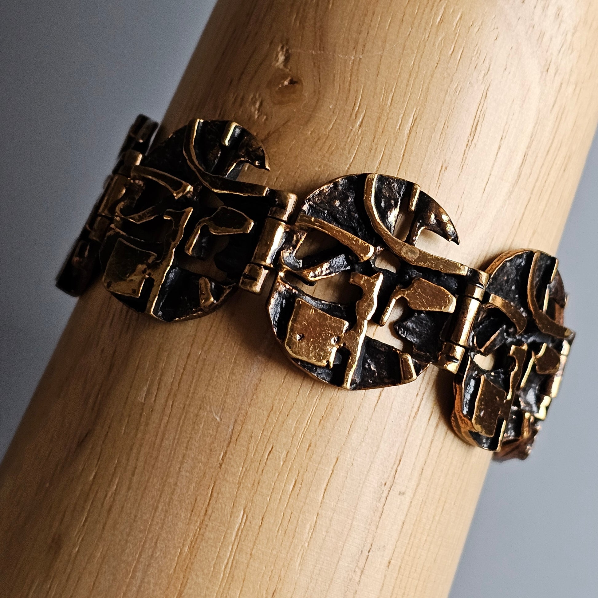 Ornate bronze bracelet with a textured, abstract leaf-like design.