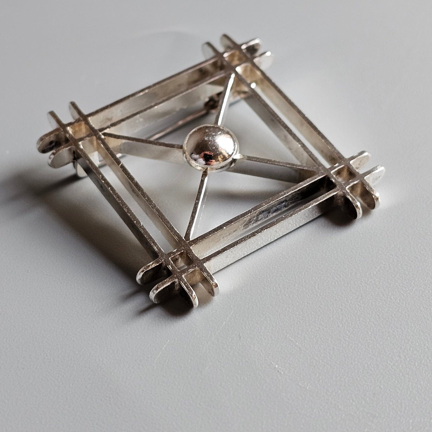 Geometric metal structure with a central sphere and four triangular sides.