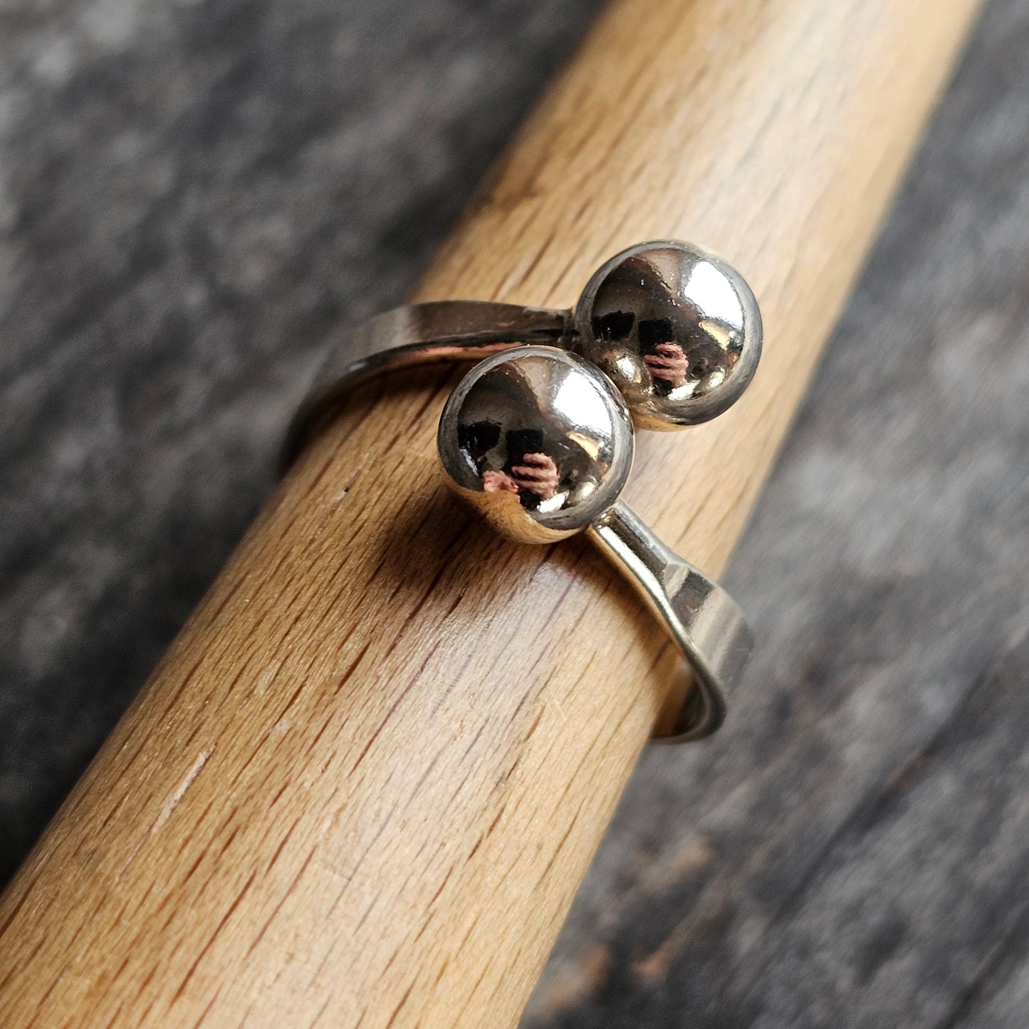 Silver ring with two spherical beads on top.