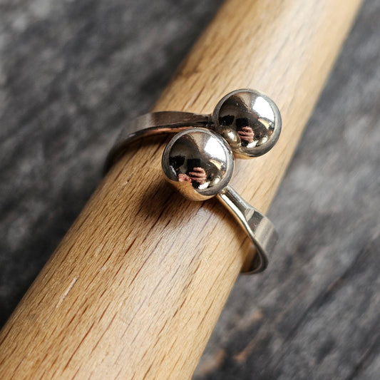 Silver ring with two spherical beads on top.