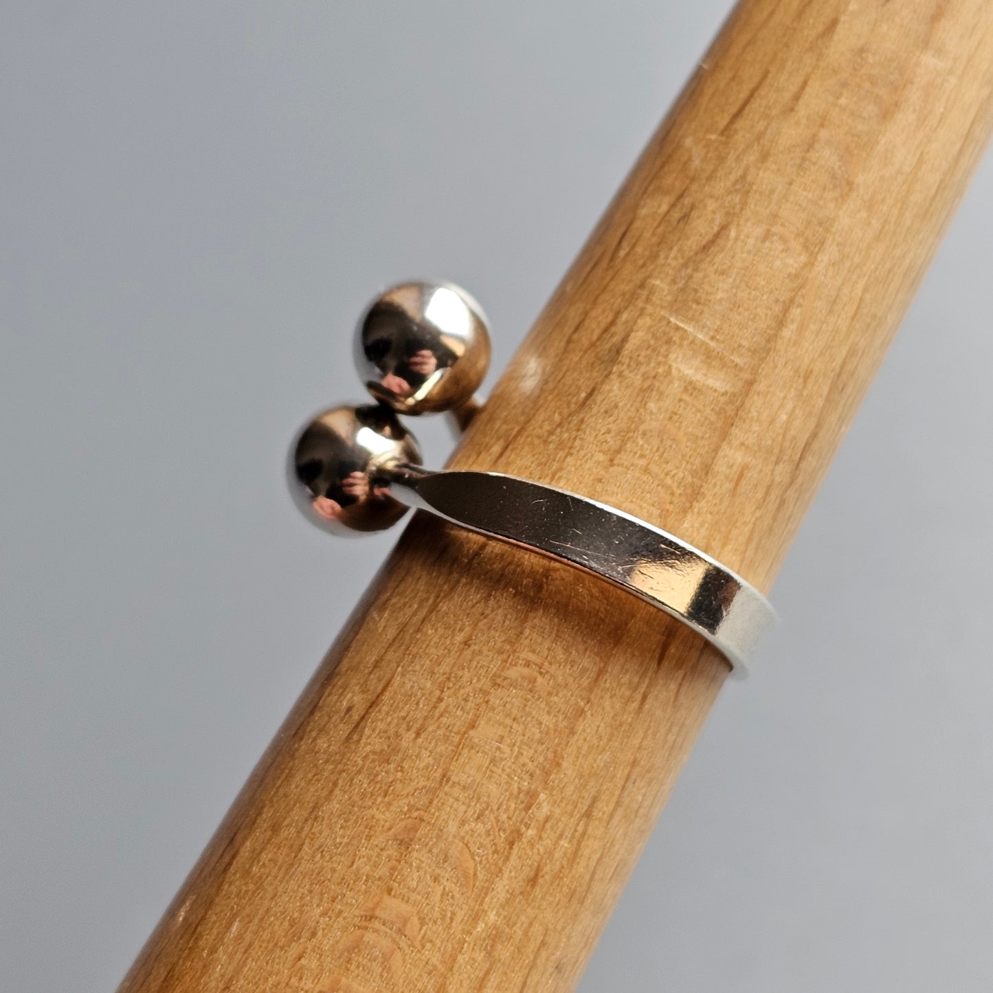 Silver ring with two spherical beads attached to a flat band.