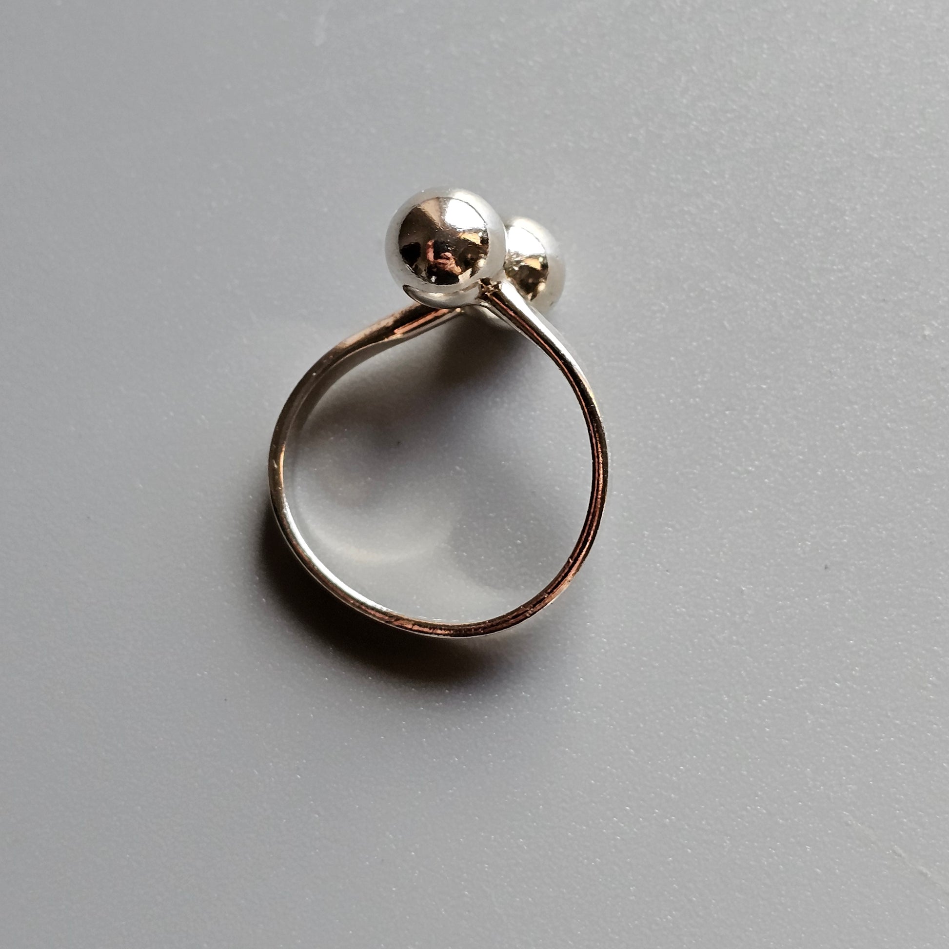 Silver ring with two spherical beads on top.