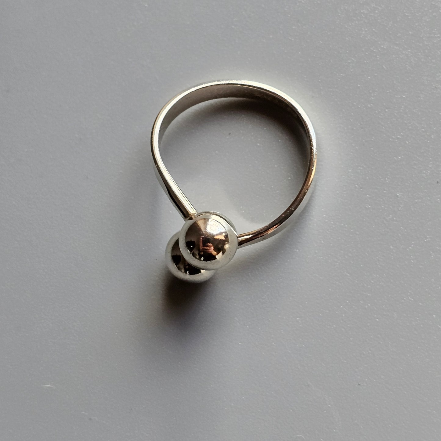 Silver ring with a spherical charm or bead attached.