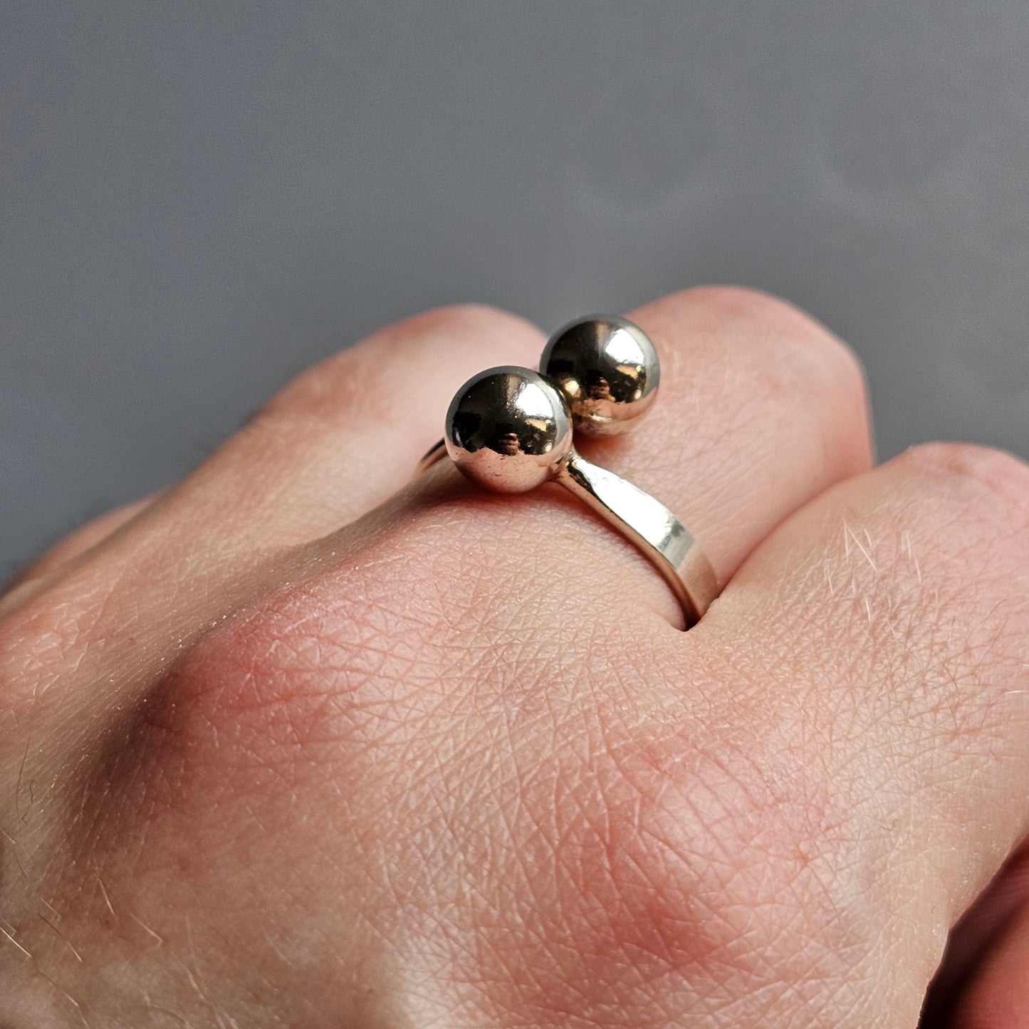 Silver ring with two spherical beads on top.