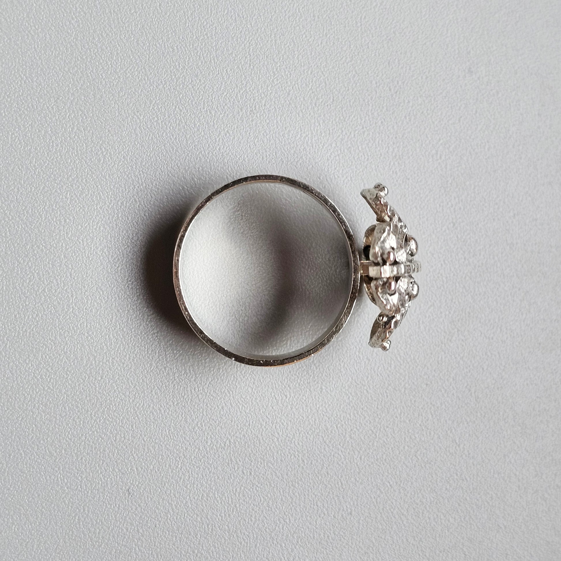 Silver ring with an ornate butterfly-shaped design on top.