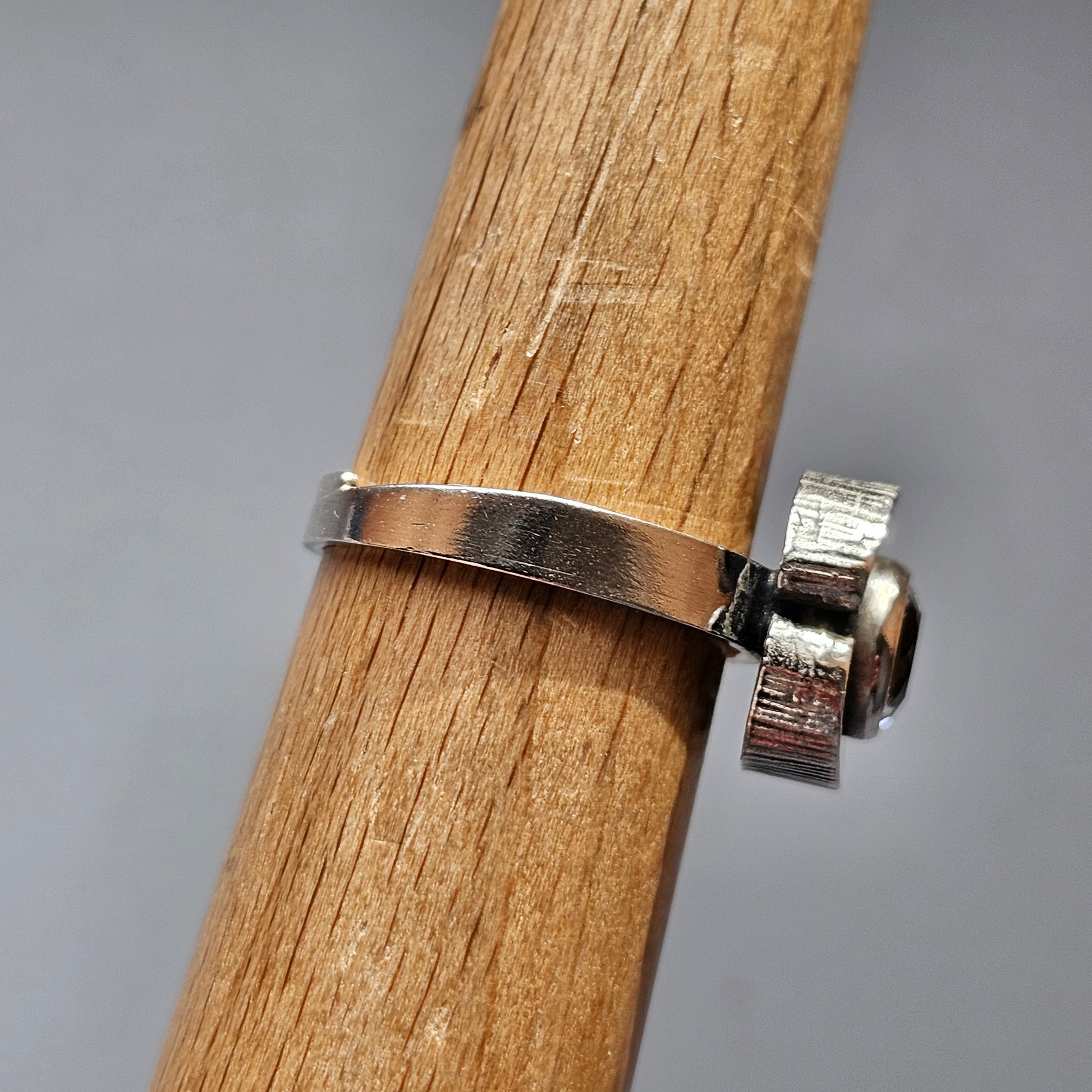 Metal hose clamp or pipe clamp wrapped around a wooden pole or dowel.