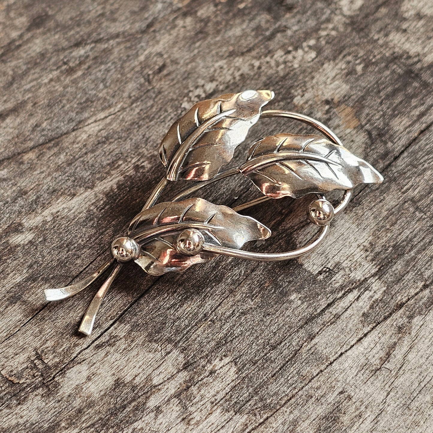 Vintage silver leaf-shaped brooch with delicate floral design.