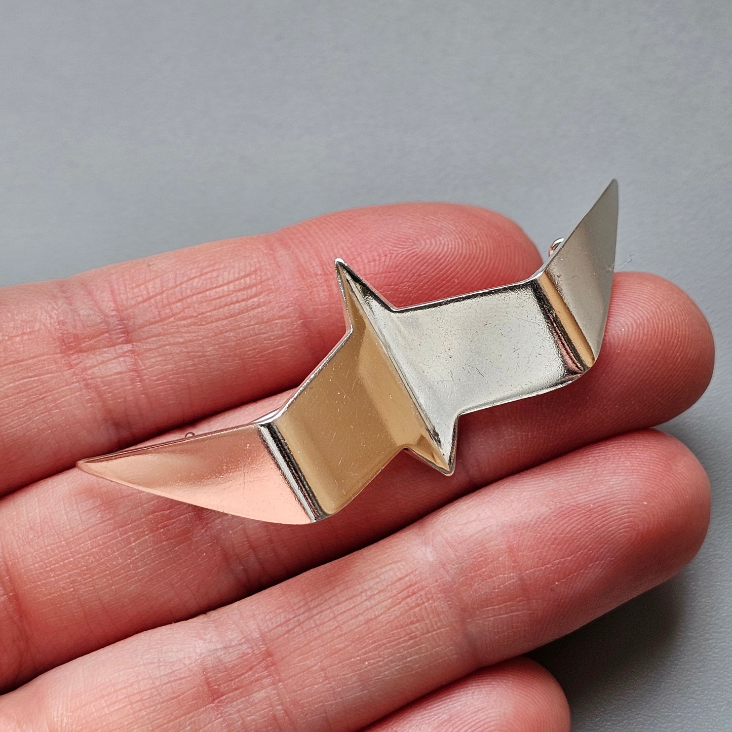 Metallic star-shaped object held between fingers.