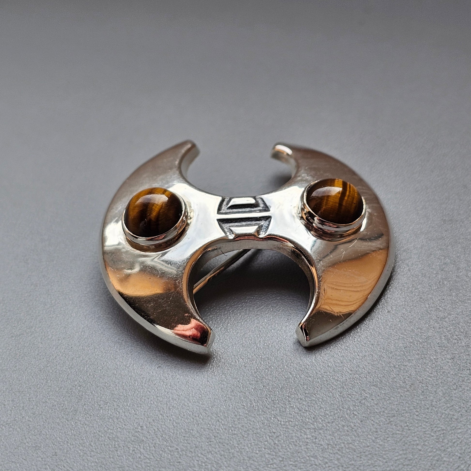 Crescent-shaped silver ring with two amber-colored gemstones.