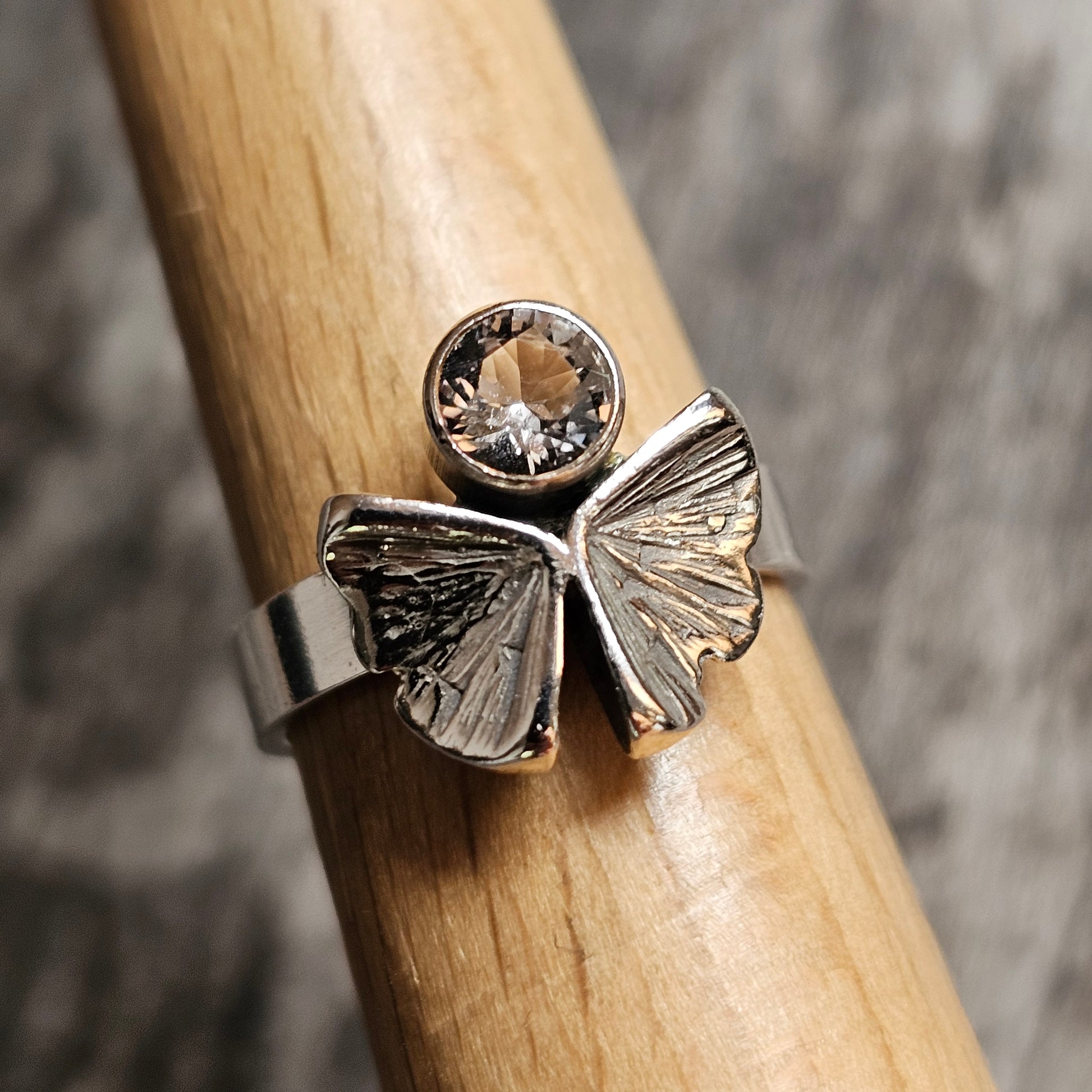 Silver ring featuring a butterfly design with a gemstone above it.