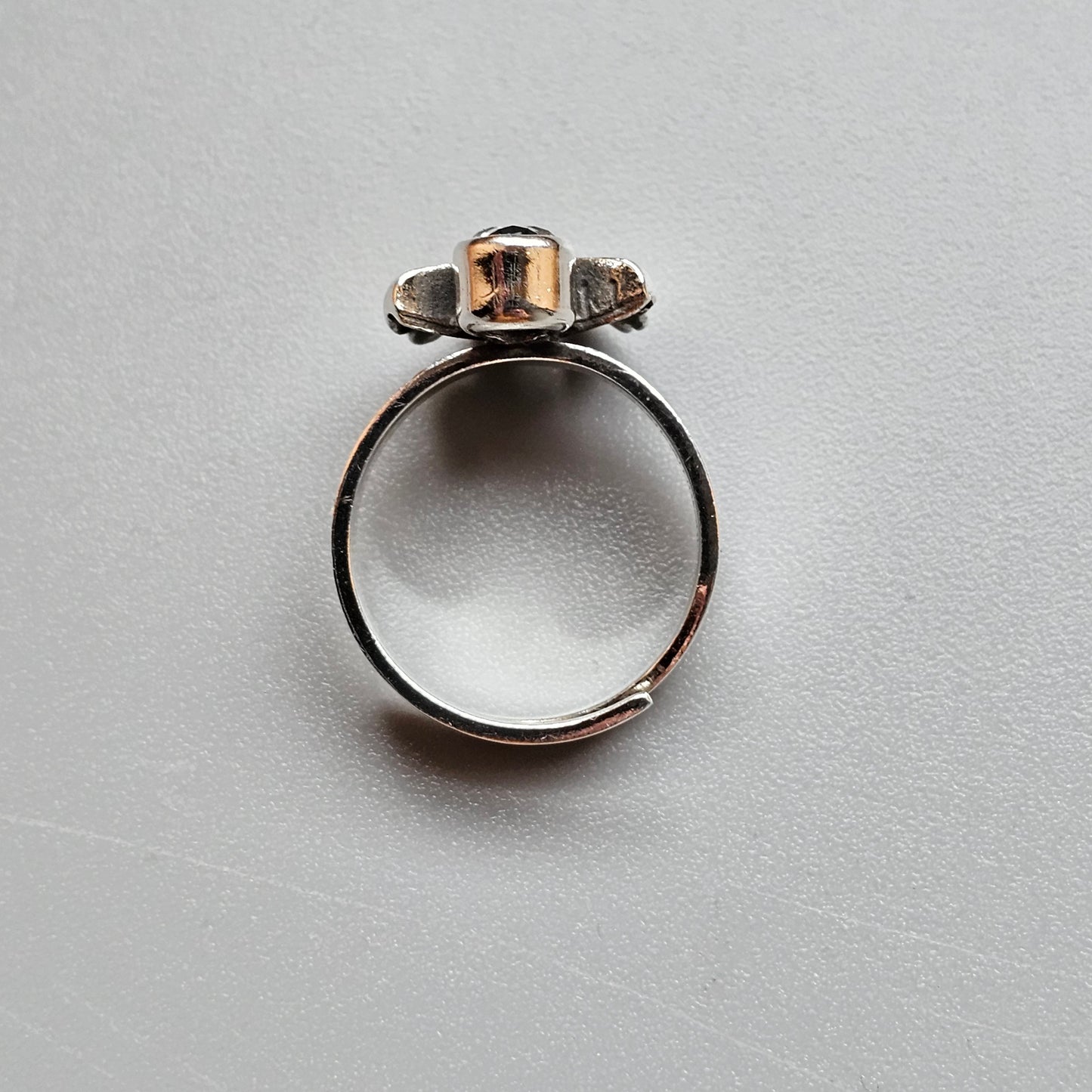 Silver ring with a unique top featuring three small gemstones or crystals.