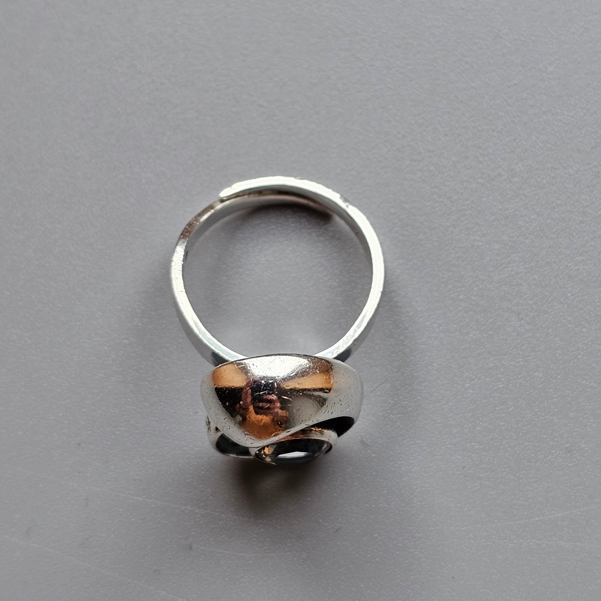 Silver ring with a wide, polished band featuring an abstract curved design.