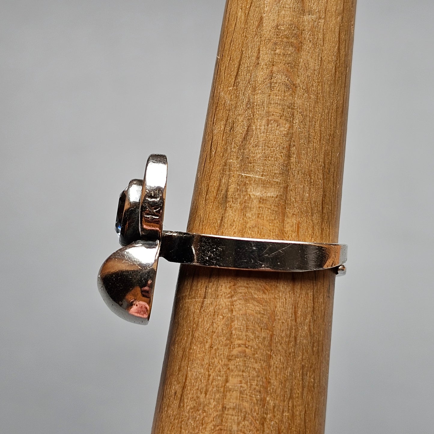 Silver ring with a curved design wrapped around a wooden surface.