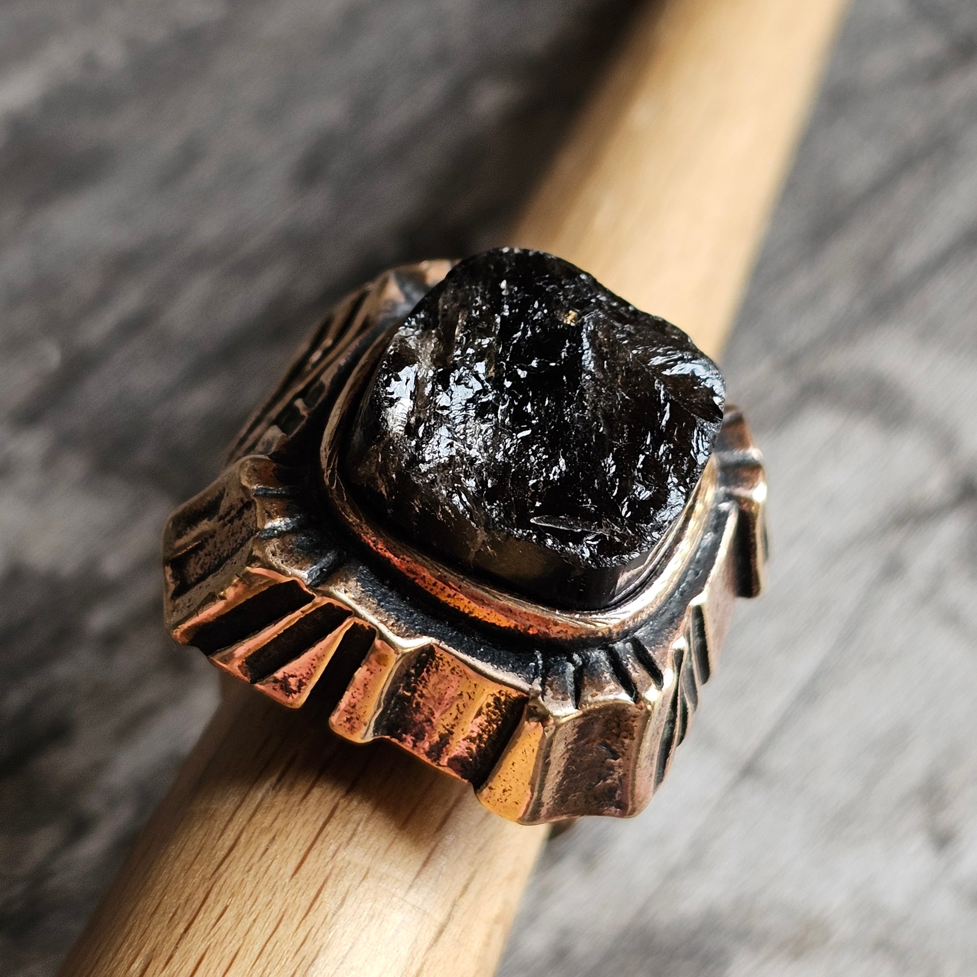 Ring featuring a rough black stone set in an ornate copper-toned metal band.