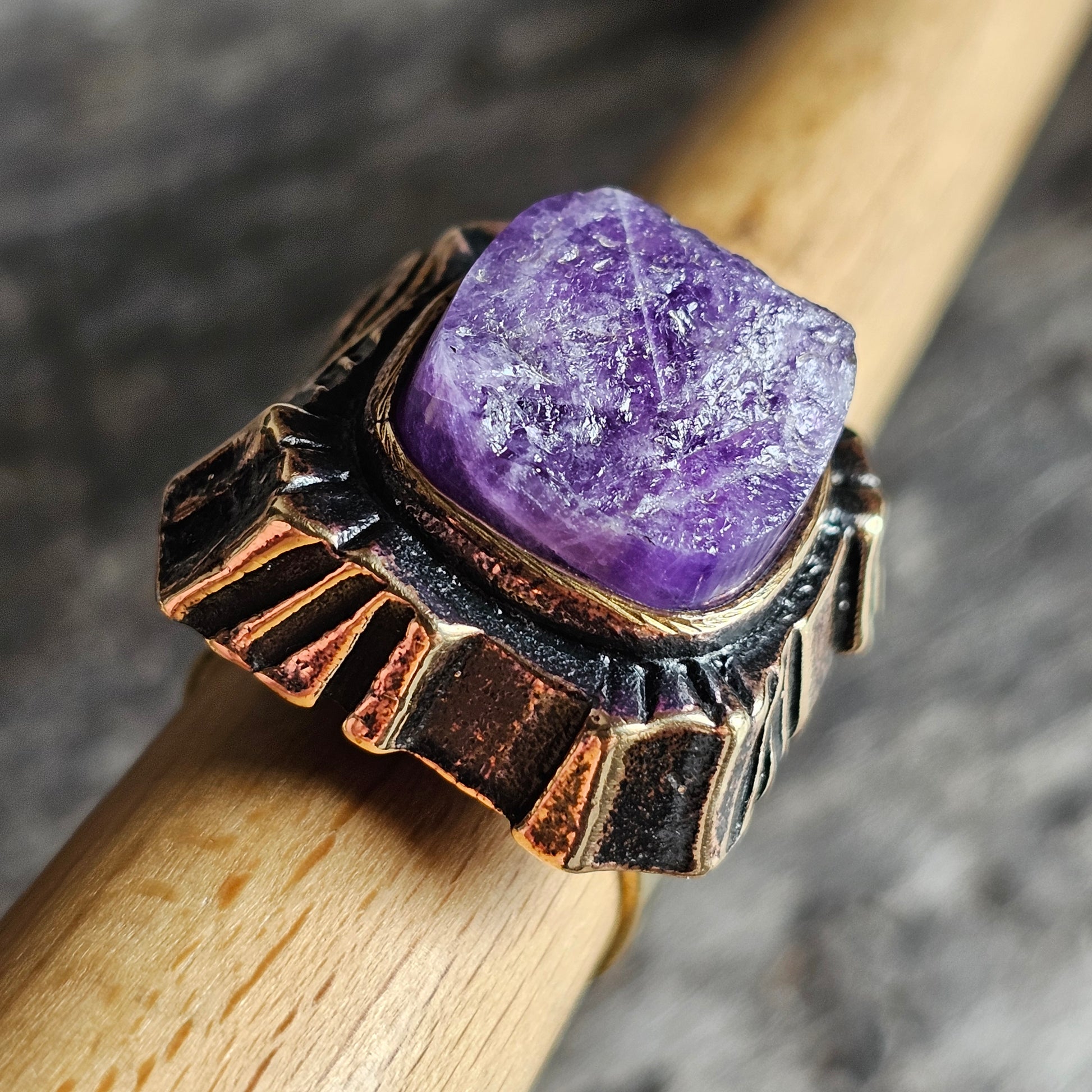 Ornate ring featuring a rough amethyst crystal set in a decorative metal band.