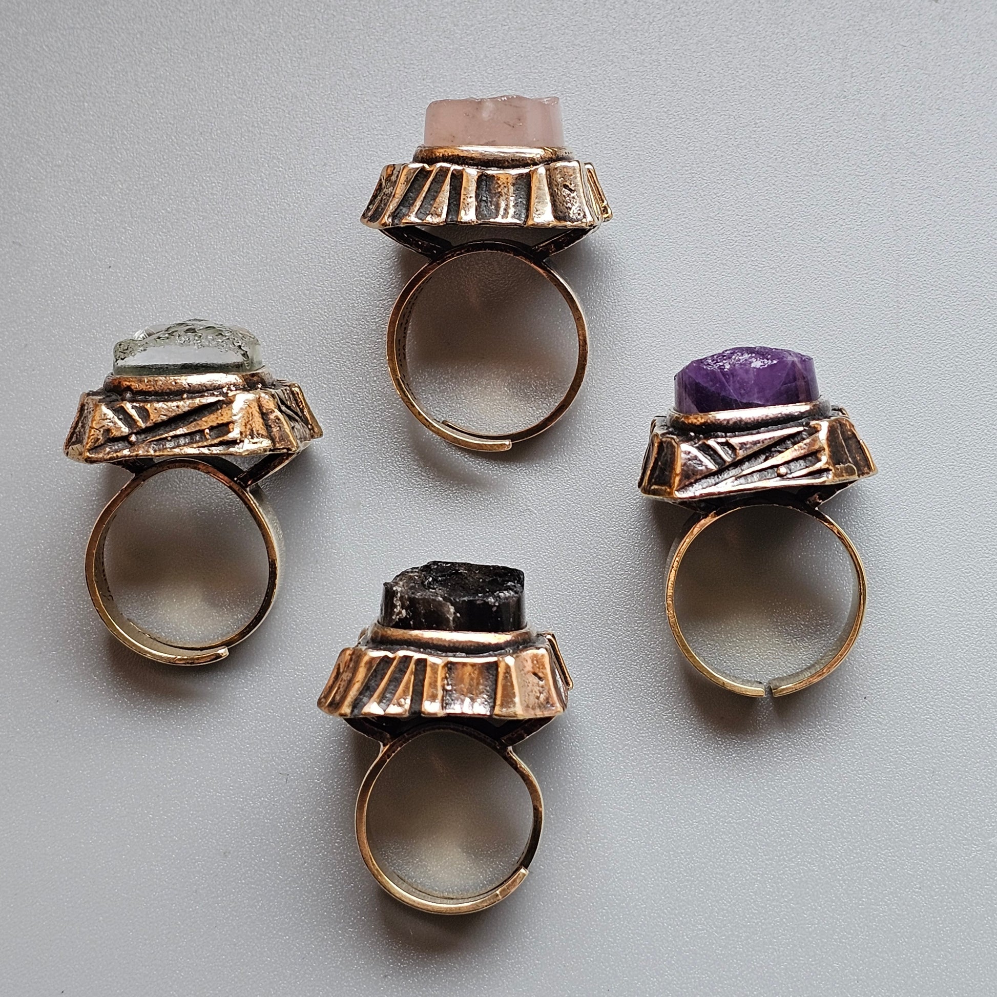 Four ornate rings with large gemstones set in decorative gold-toned metal settings.