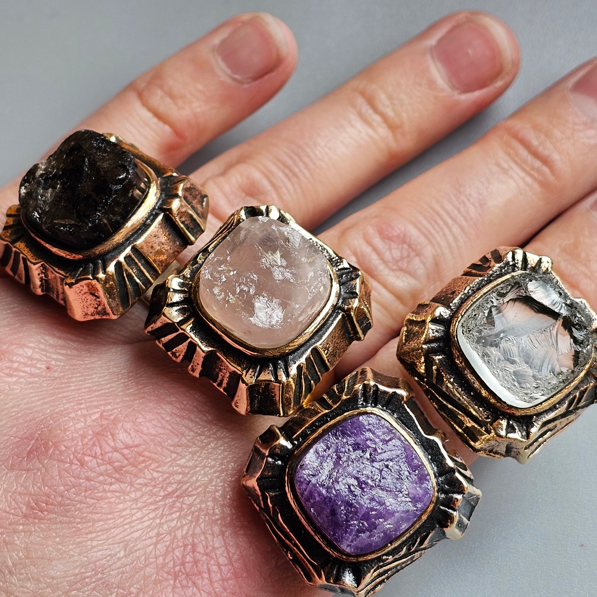 Ornate gemstone rings with chunky metalwork settings worn on fingers.