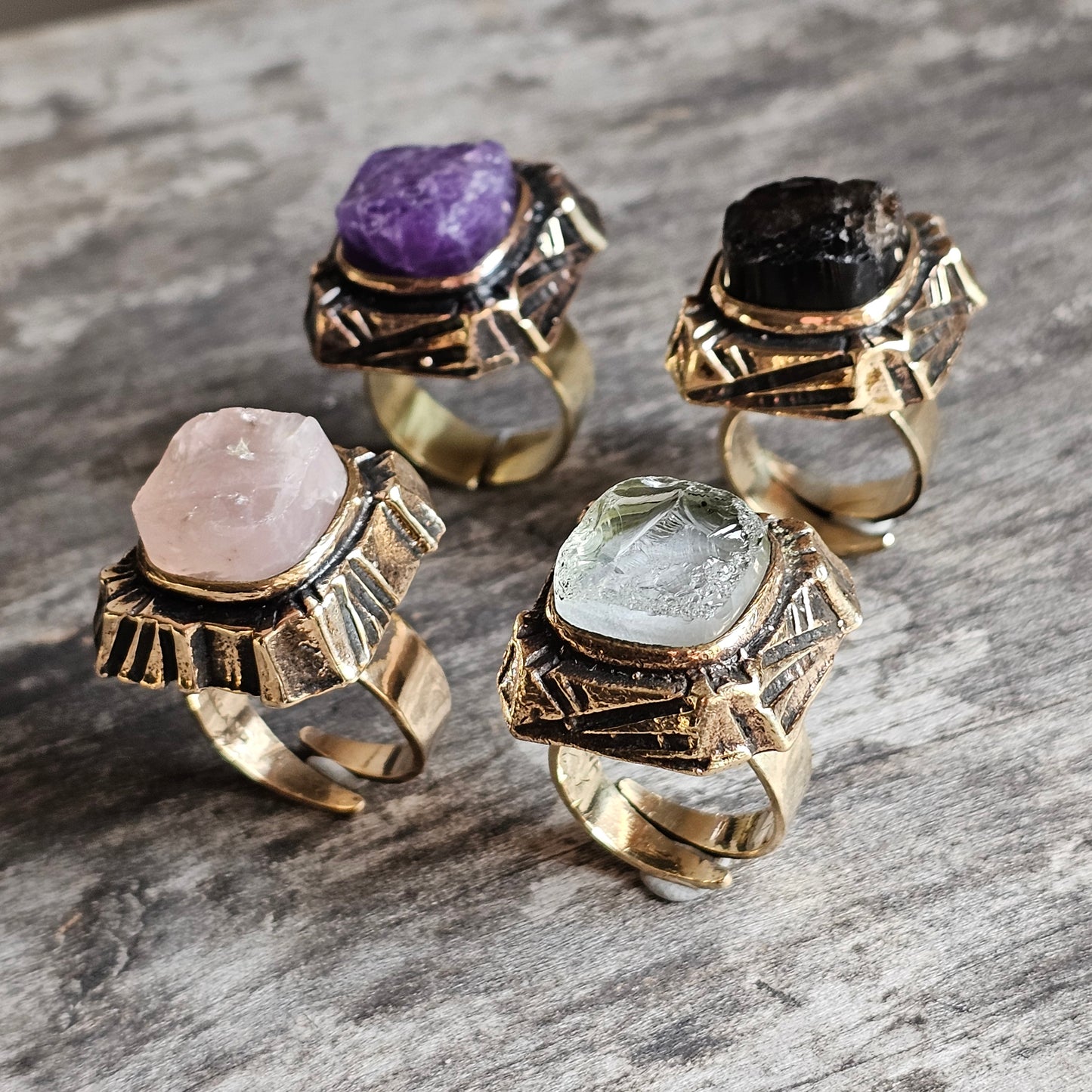 Four ornate rings with different colored gemstones set in gold-toned metal.