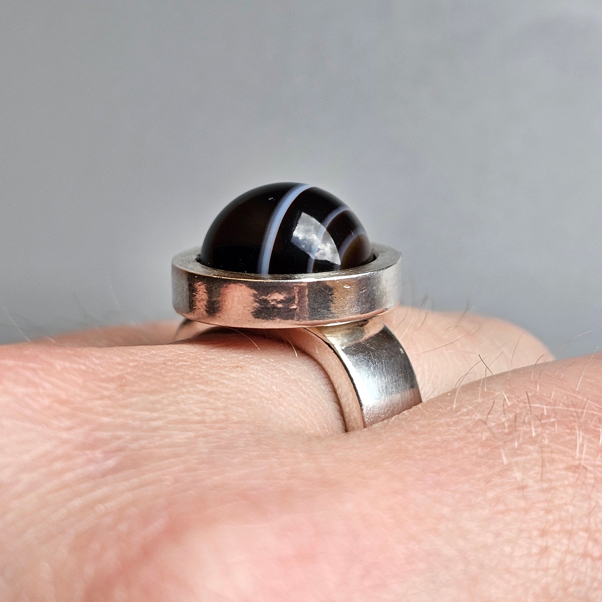 Silver ring with a black domed stone or bead set in a circular bezel.