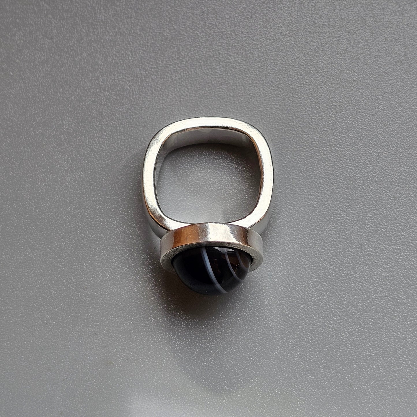 Silver ring with a rounded black stone or gem set in it.