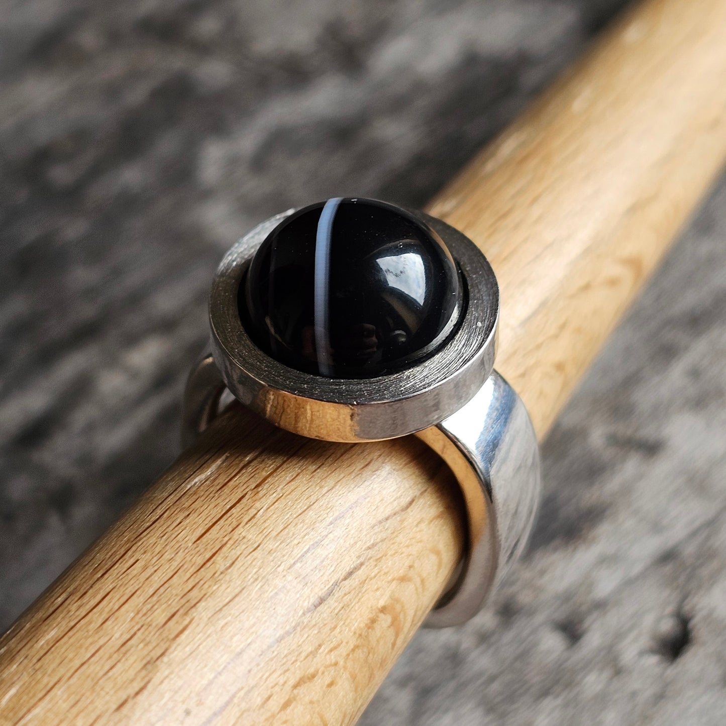 Silver ring with a round black stone or bead as its centerpiece.